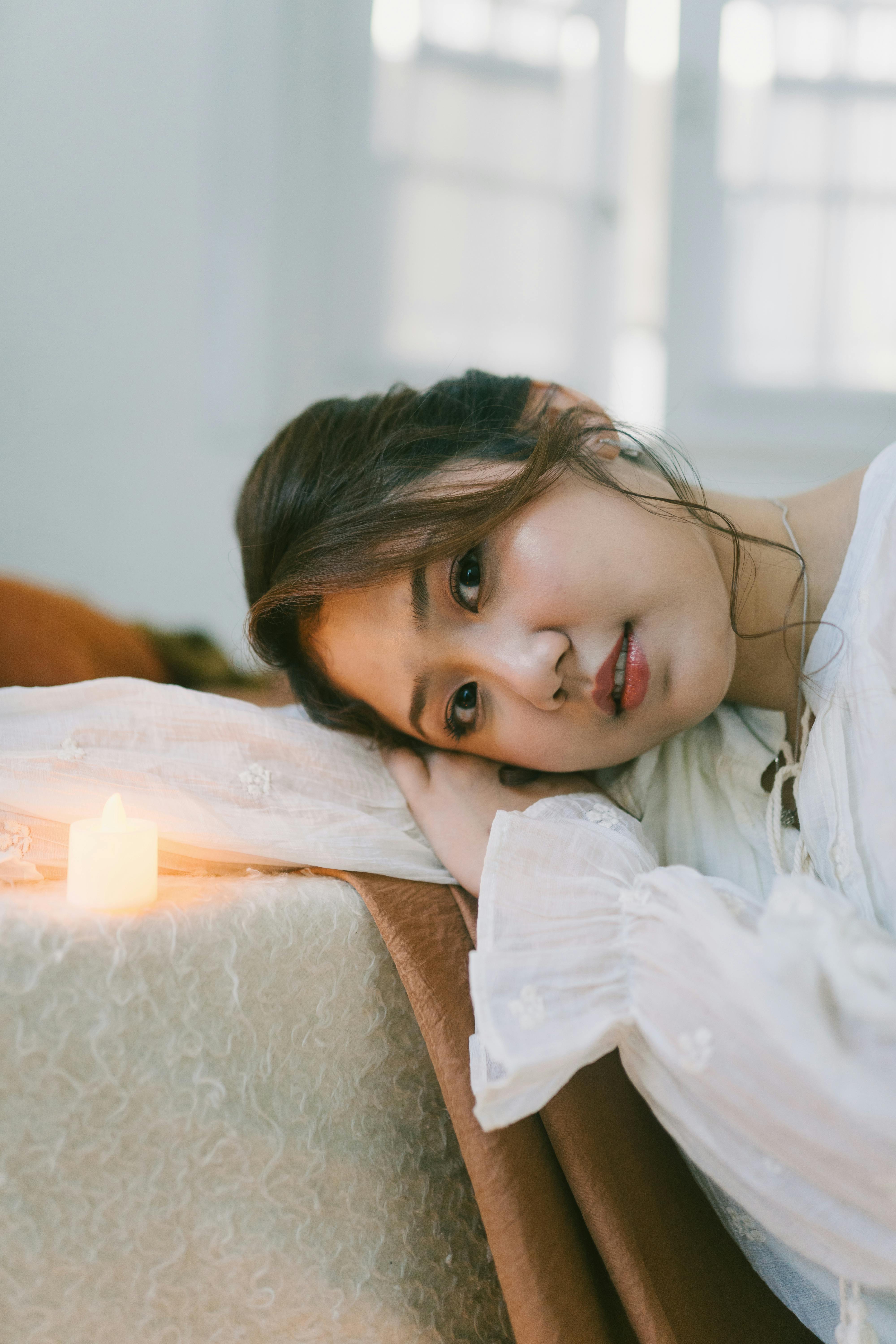 Serene woman resting peacefully by the warm glow of a single candle, soft ambient lighting highlighting her relaxed features