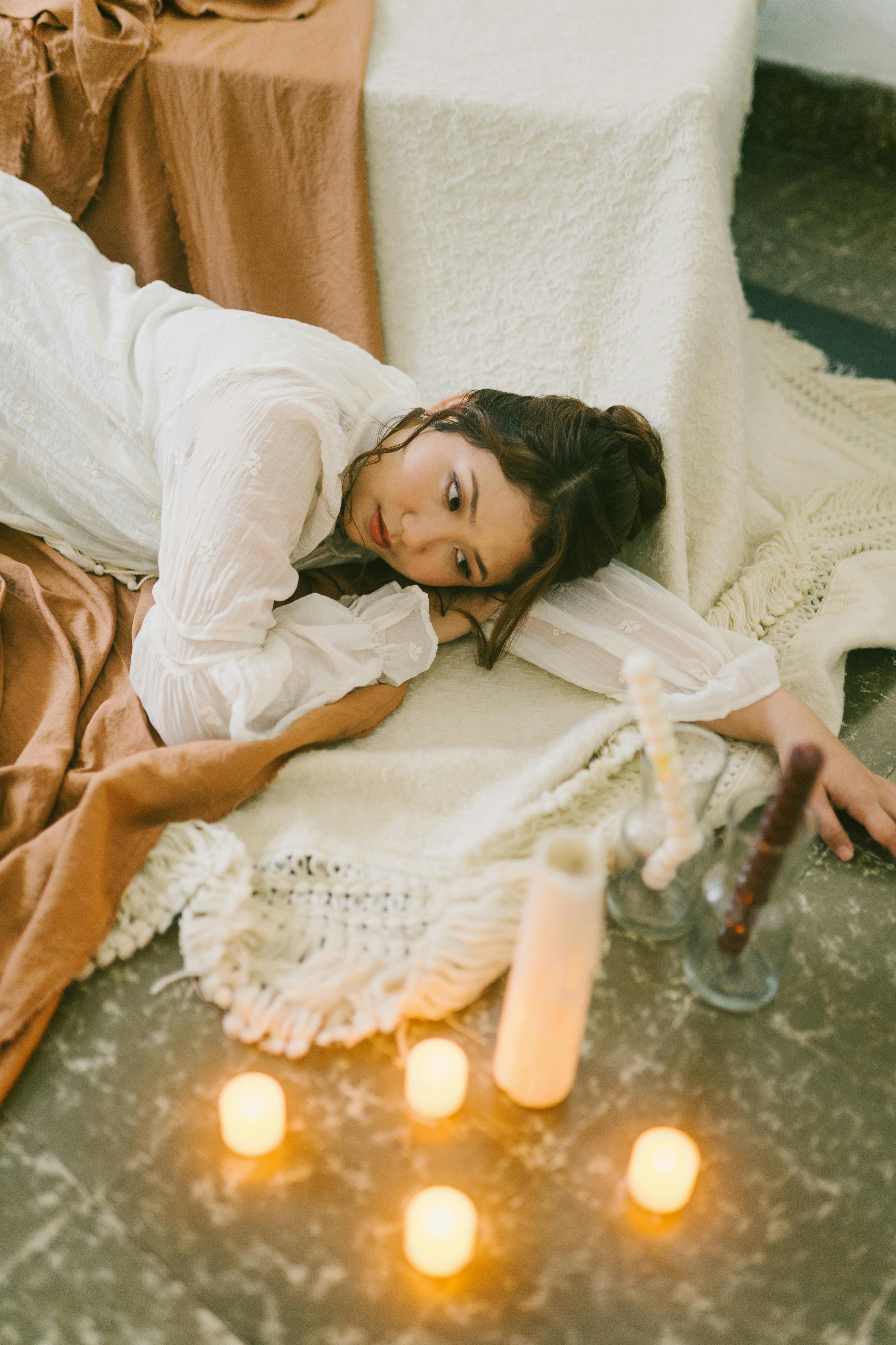 Miễn phí Người phụ nữ nằm nghỉ trên những tấm chăn, xung quanh là những ngọn nến tạo nên một bầu không khí thanh bình. Ảnh lưu trữ