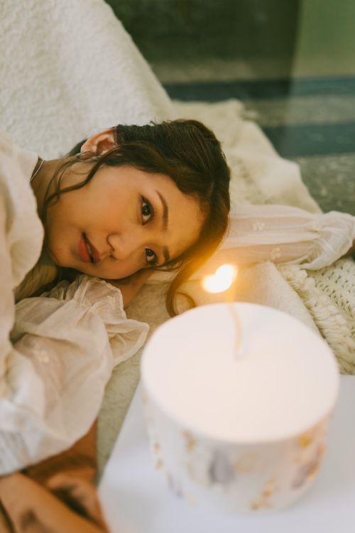 Free Woman resting by candlelight, creating a serene and intimate atmosphere indoors. Stock Photo