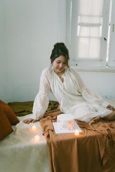 Young woman celebrating a birthday with a cake and candles in a cozy setting.