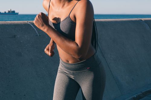 Free Fit woman running along a seafront wall in athletic wear, showcasing strength and determination. Stock Photo