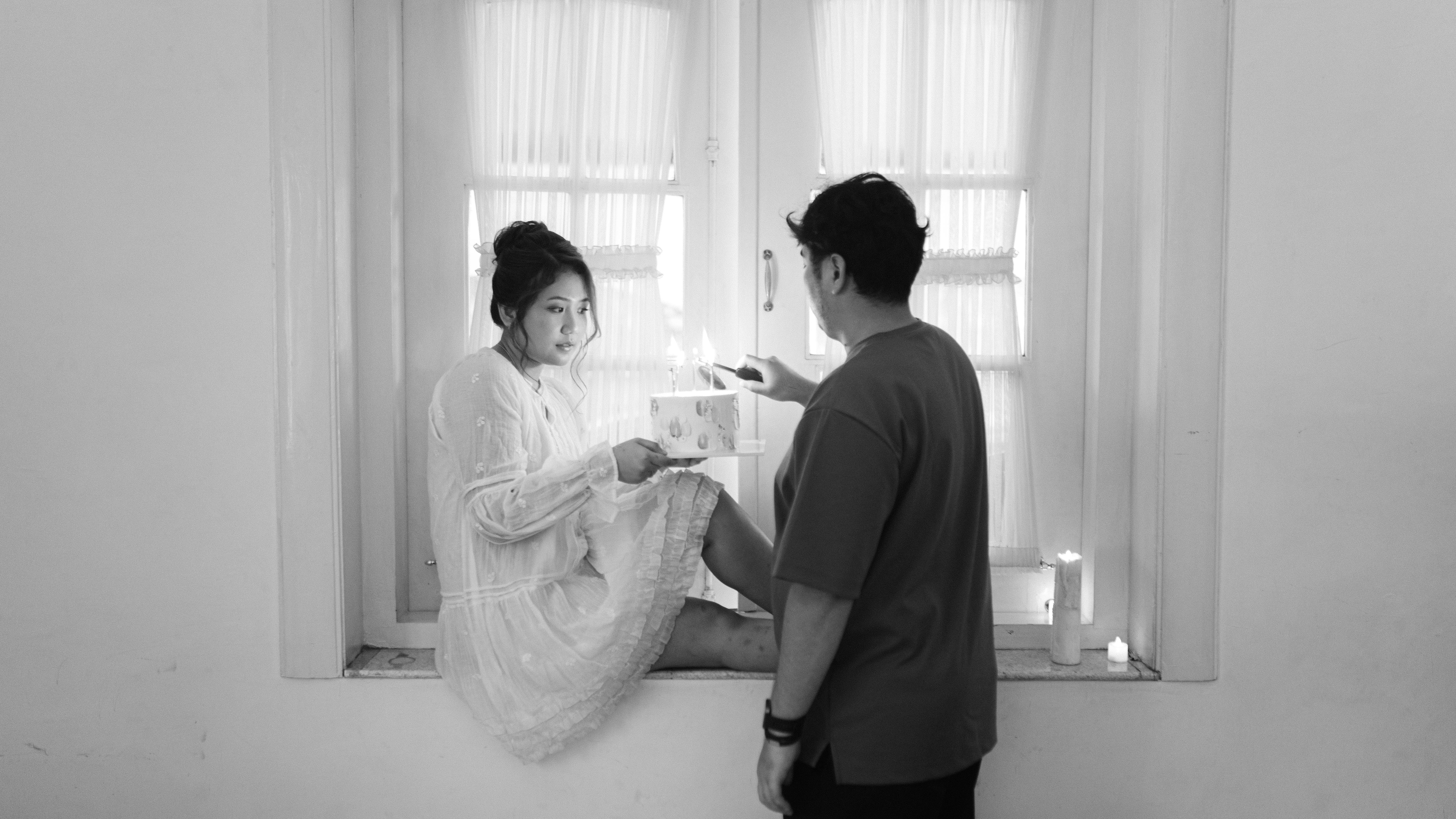 Gratuit O scenă intimă în alb-negru, în interior, cu un cuplu care împarte un tort cu lumânări aprinse. Fotografie de stoc