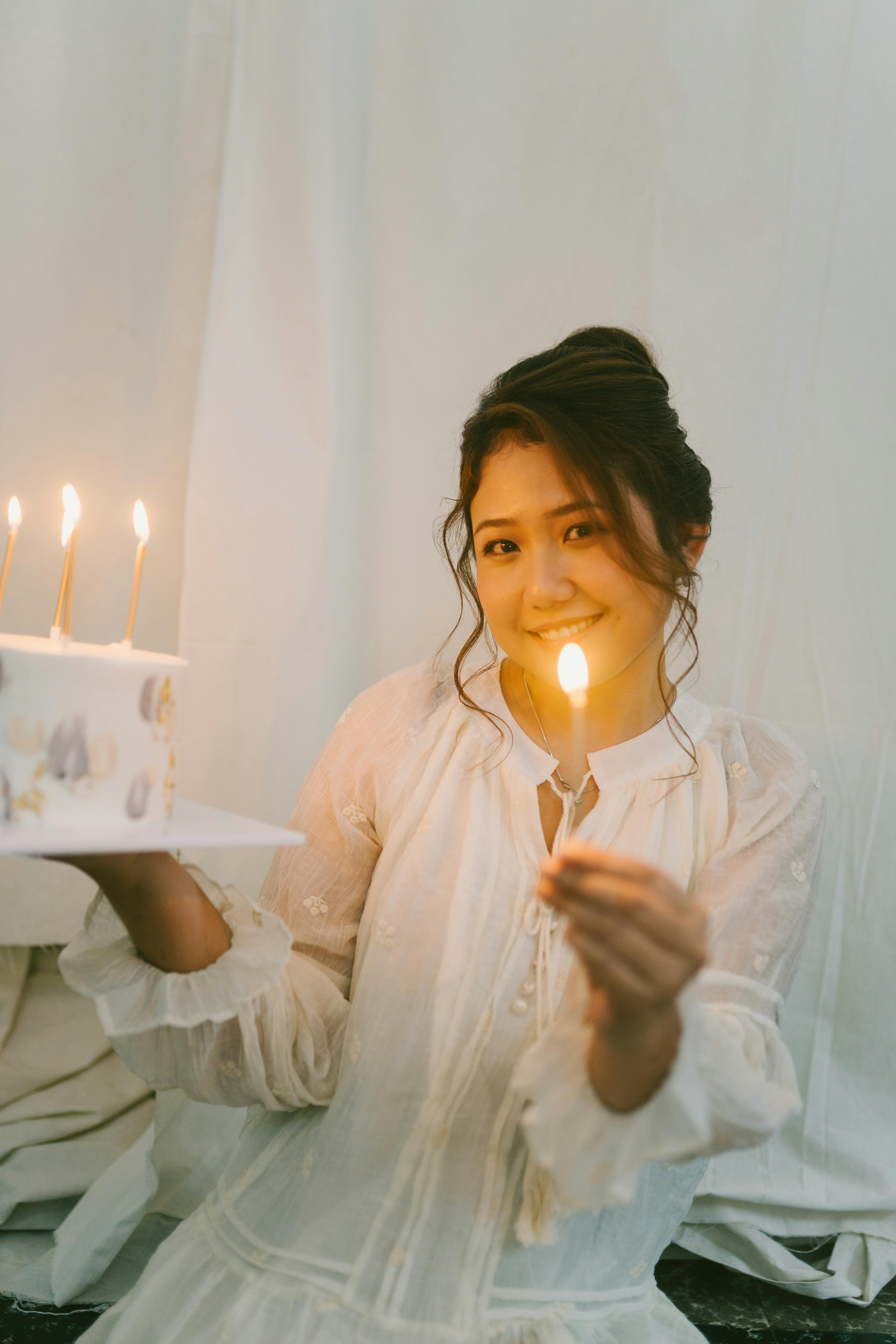 bezplatná Veselá žena držící zapálenou svíčku a dort pro oslavu narozenin uvnitř. Základová fotografie