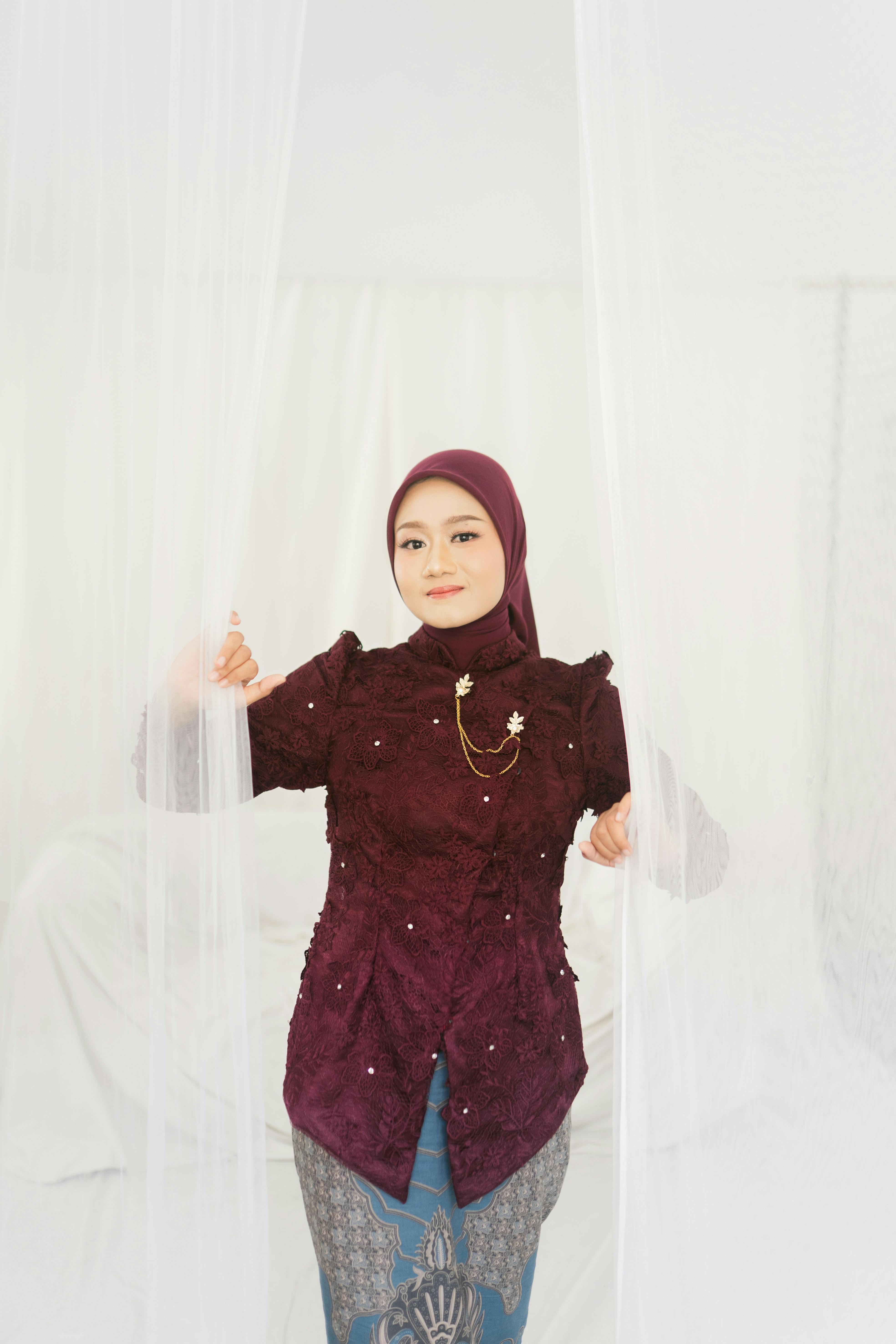 Bezpłatne Elegancka kobieta ubrana w hidżab i tradycyjny strój pozuje w pomieszczeniu ze spokojnym wyrazem twarzy. Zdjęcie z galerii