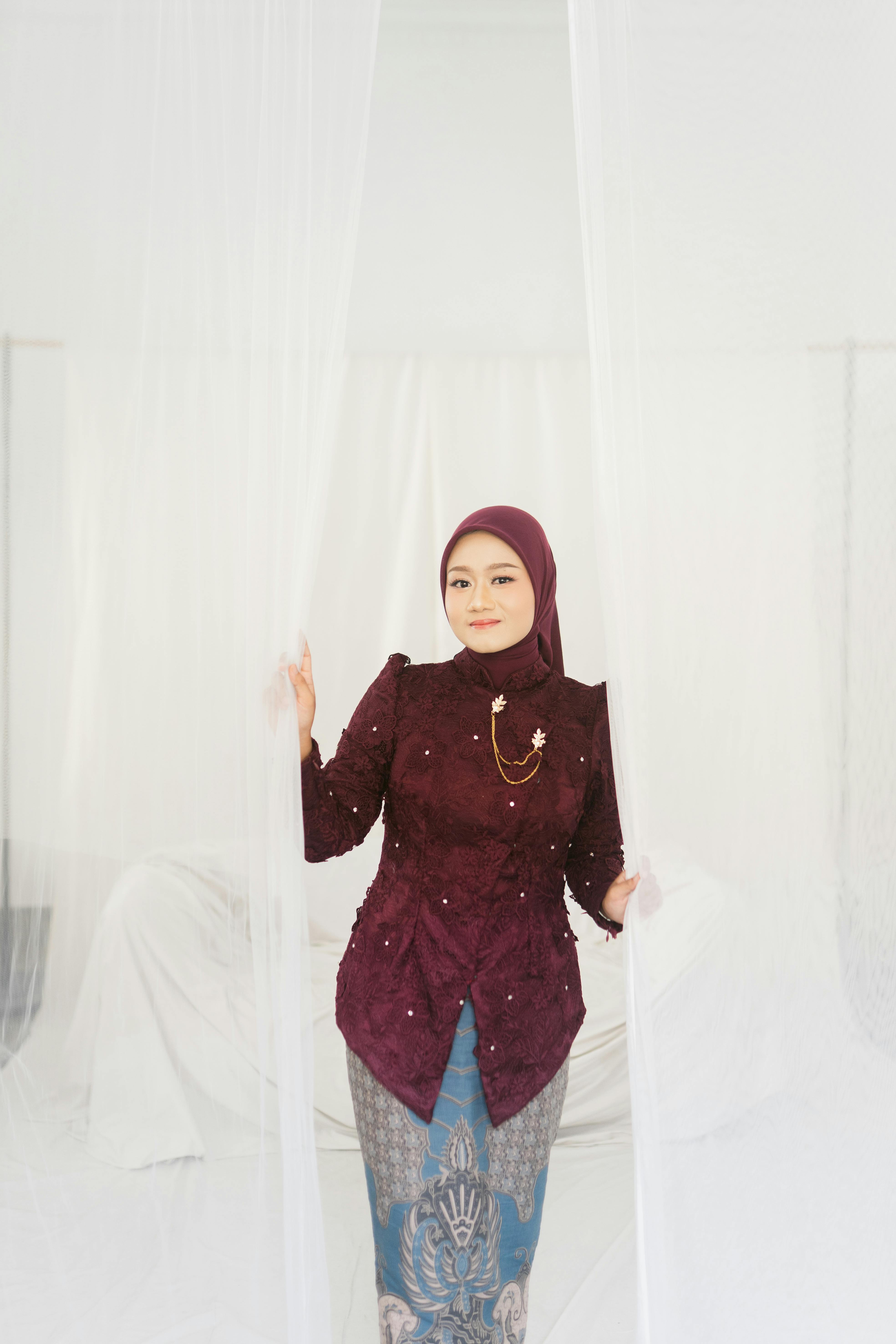 Ücretsiz Geleneksel kıyafetler giymiş bir kadın, yumuşak perdelerle çevrili iç mekanda zarif bir şekilde poz veriyor. Stok Fotoğraflar