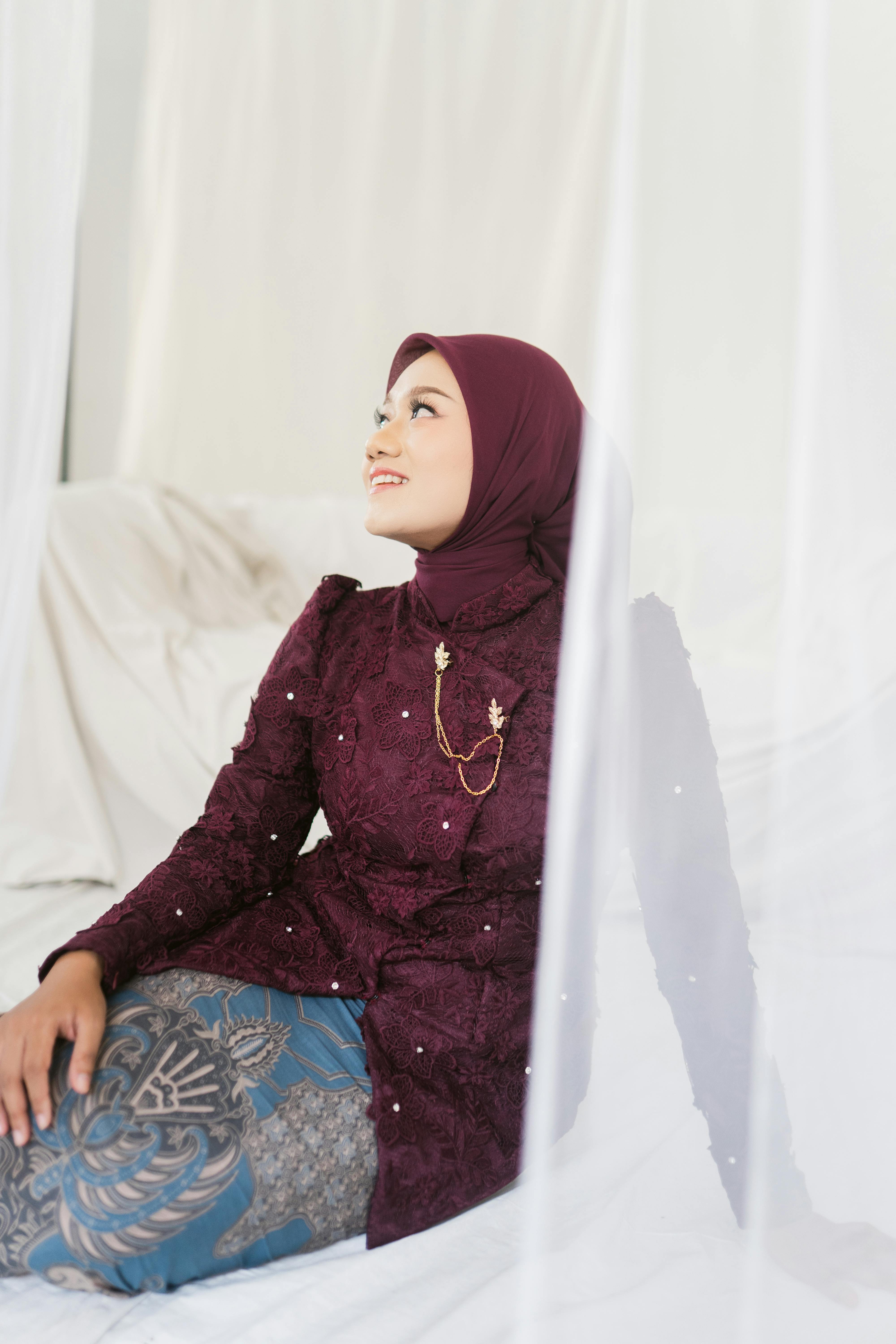 bezplatná Žena v tradičním oděvu s hidžábem pózuje uvnitř s klidným výrazem. Základová fotografie