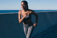 阳光明媚的日子里，一位健康的女性沿着海滨慢跑，展现了健康与活力