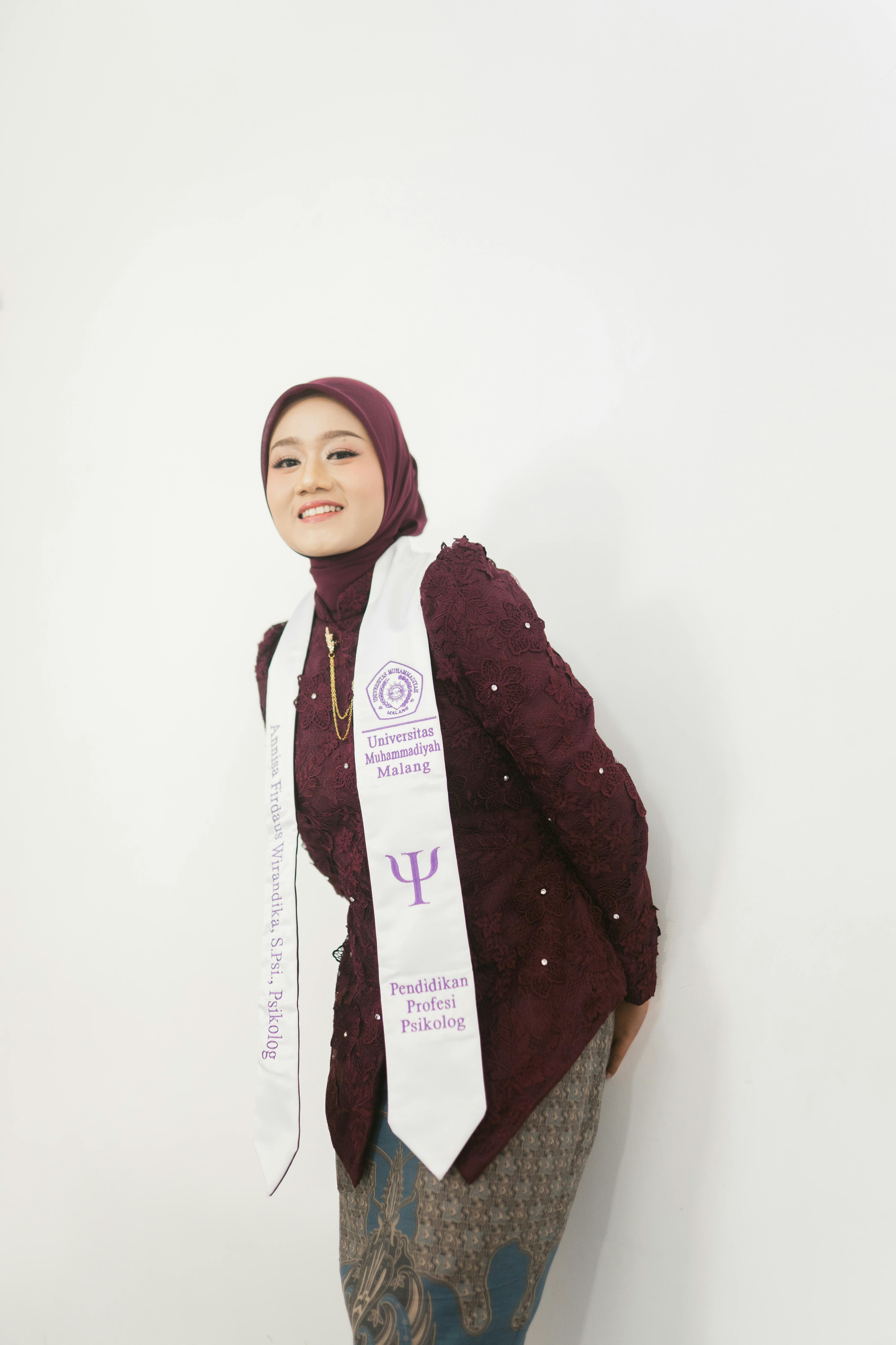 Ücretsiz Geleneksel kıyafetler giymiş genç bir kadın, beyaz bir arka plan önünde mezuniyet şalıyla poz veriyor. Stok Fotoğraflar