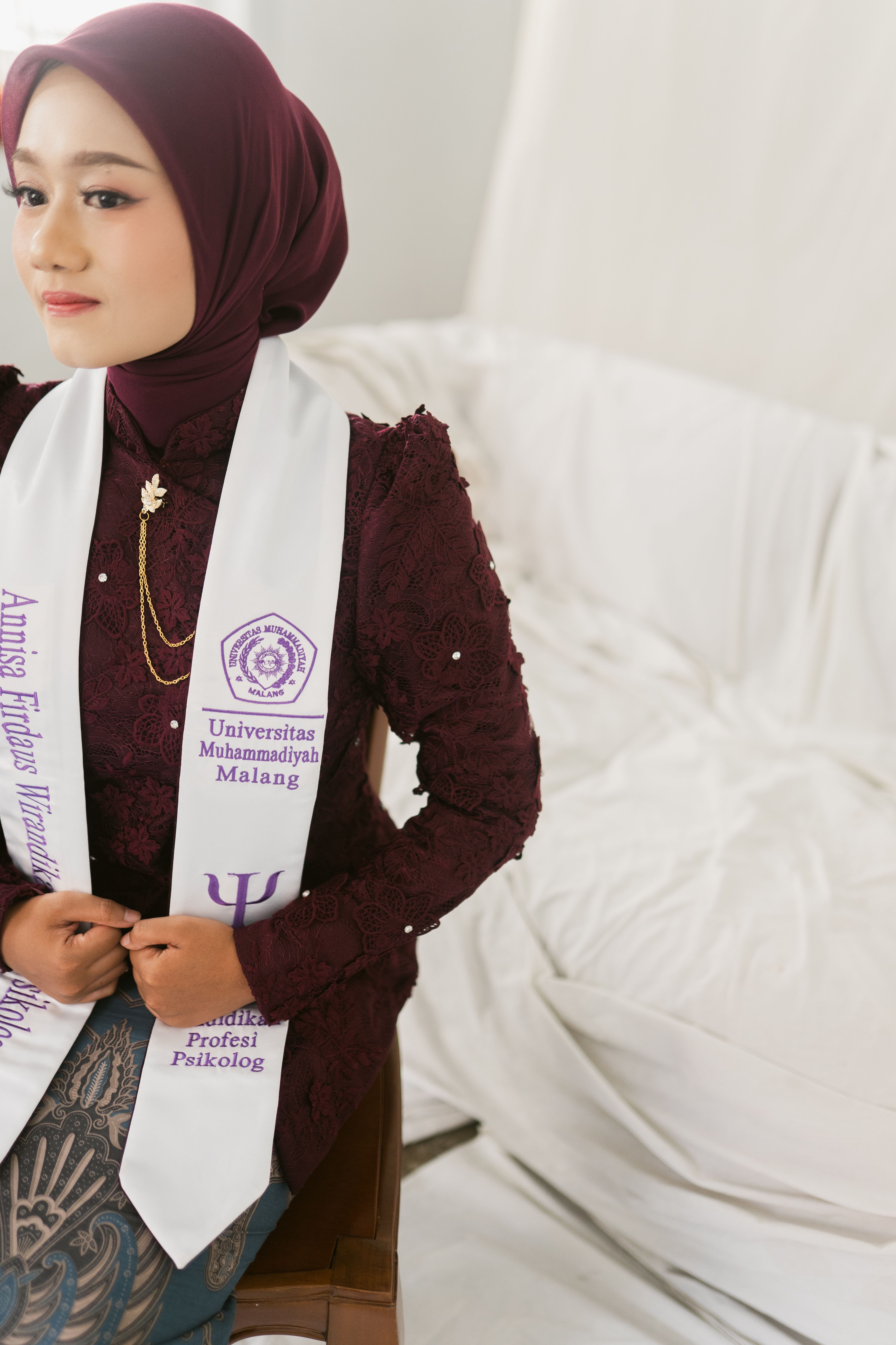Young female graduate in traditional outfit at graduation ceremony.