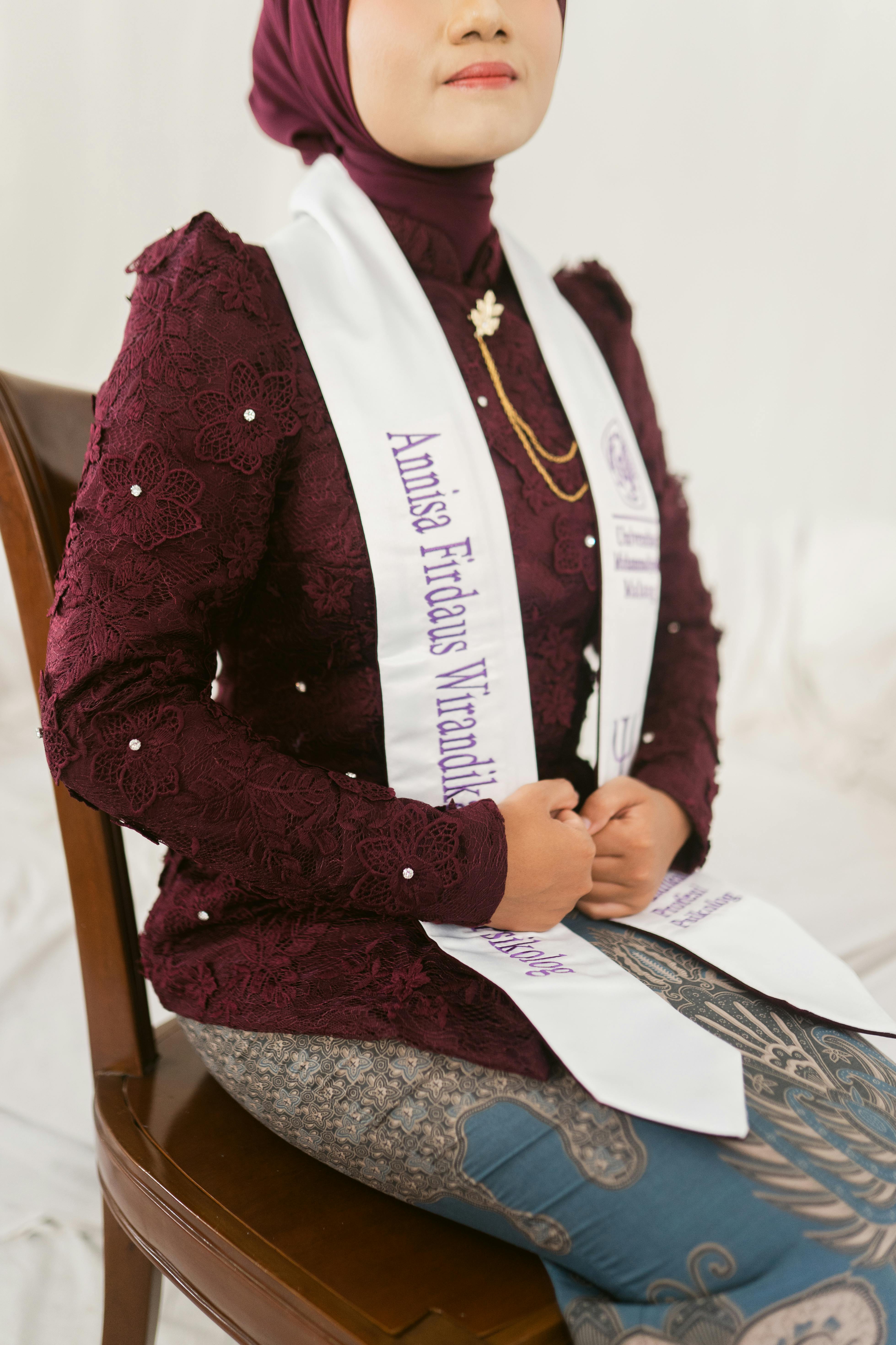 bezplatná Žena v kaštanově hnědé halence a batikované sukni sedí elegantně a má na sobě slavnostní šerpu. Základová fotografie