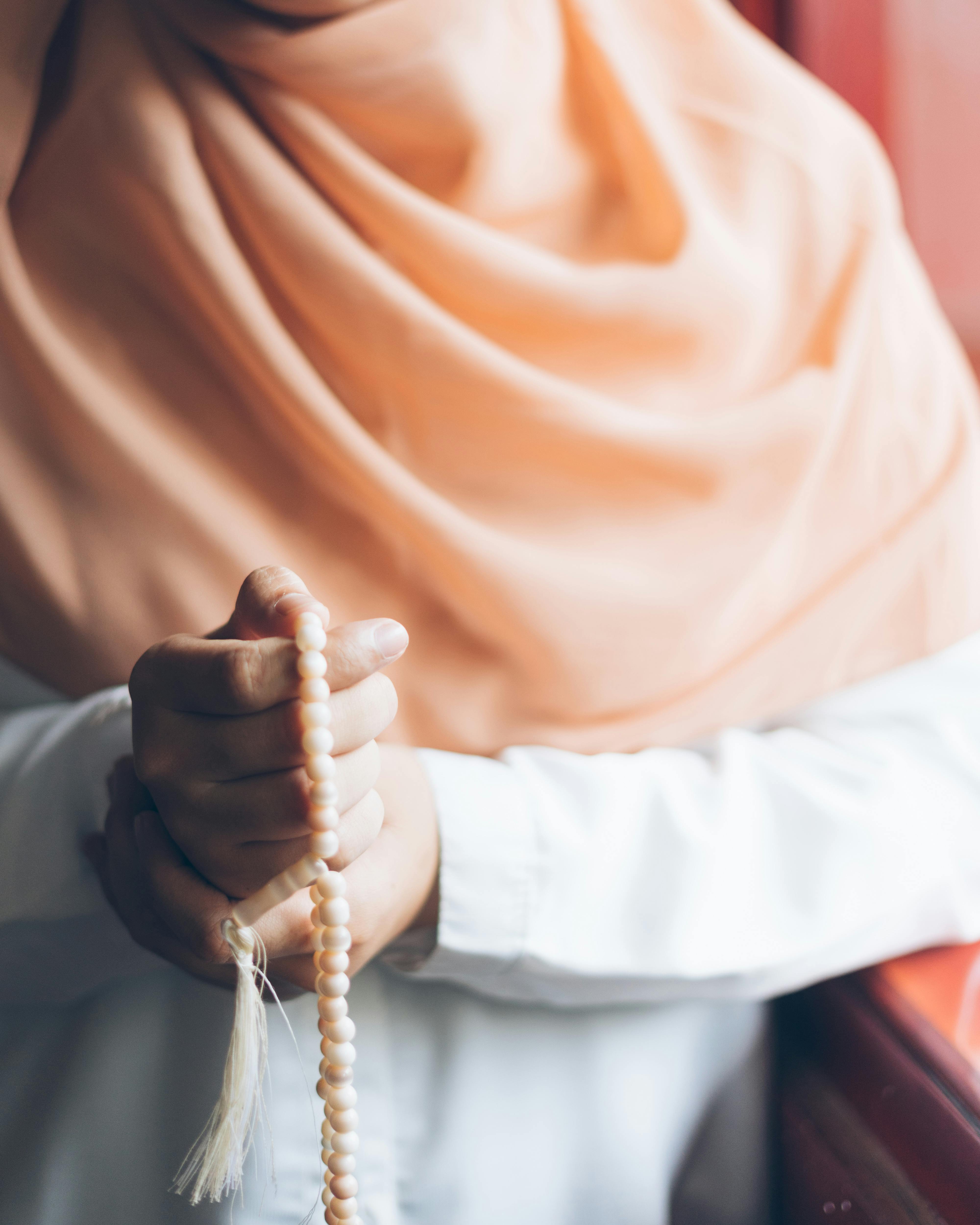Bezpłatne Zbliżenie kobiety ubranej w hidżab, trzymającej różaniec w otoczeniu duchowym. Zdjęcie z galerii