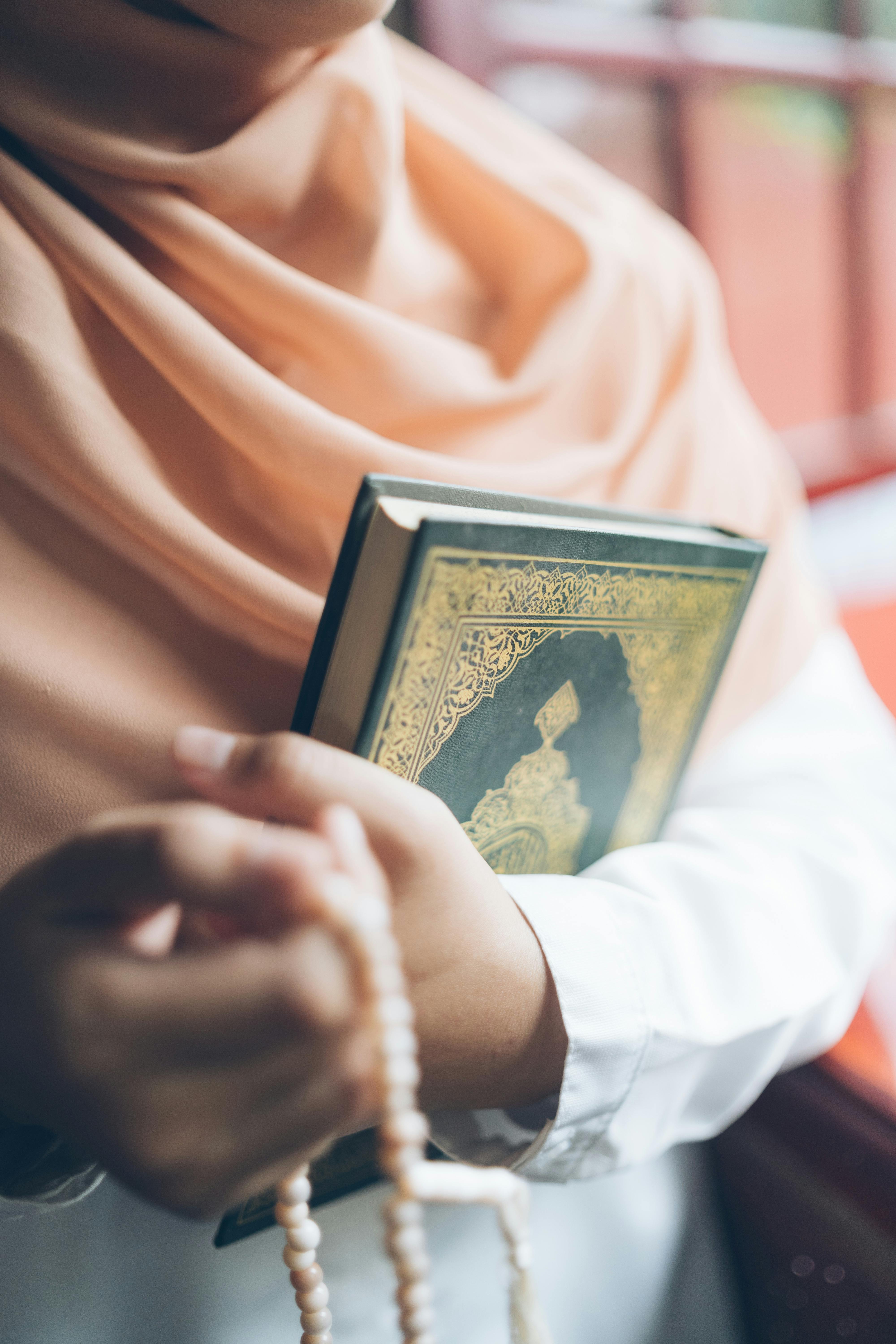 bezplatná Detail ženy v hidžábu, která drží Korán a modlitební korálky, zdůrazňující islámskou víru. Základová fotografie