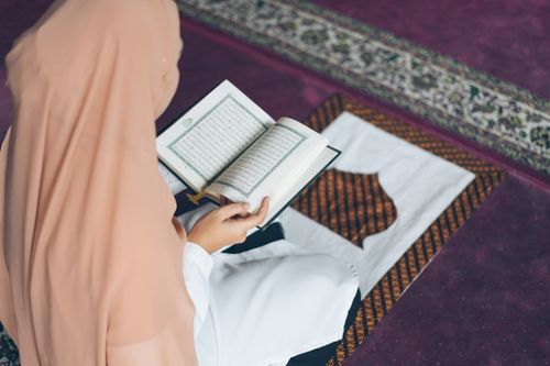 Free A woman in a prayer setting reading the Quran, focusing on spirituality and tradition. Stock Photo