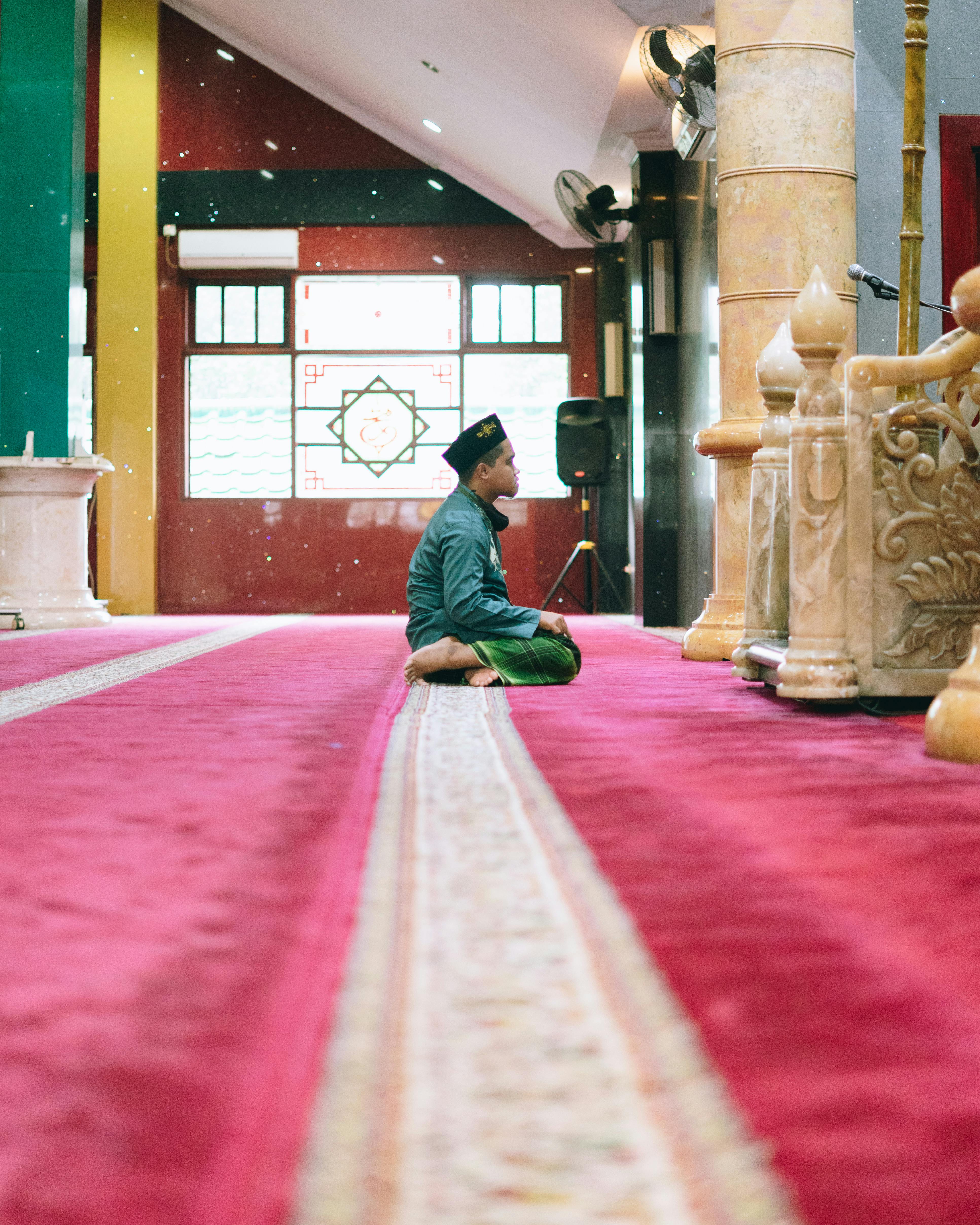 Miễn phí Một cậu bé trong trang phục truyền thống đang cầu nguyện trong một nhà thờ Hồi giáo rực rỡ sắc màu với nội thất trang trí bắt mắt. Ảnh lưu trữ
