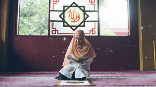 Free A young Muslim woman reading the Quran in a mosque, showcasing her faith. Stock Photo