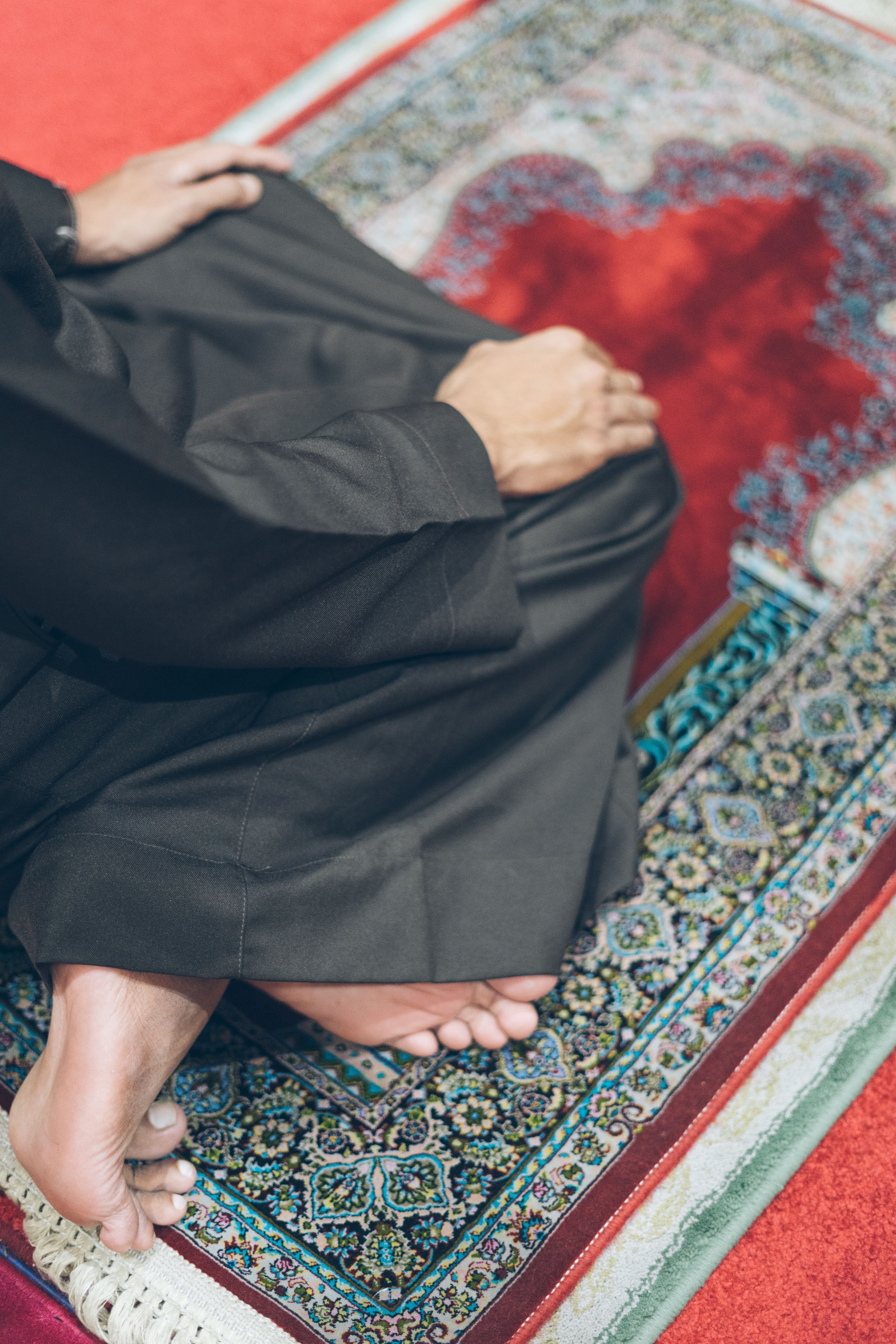 Person Praying on Ornate Prayer Rug · Free Stock Photo