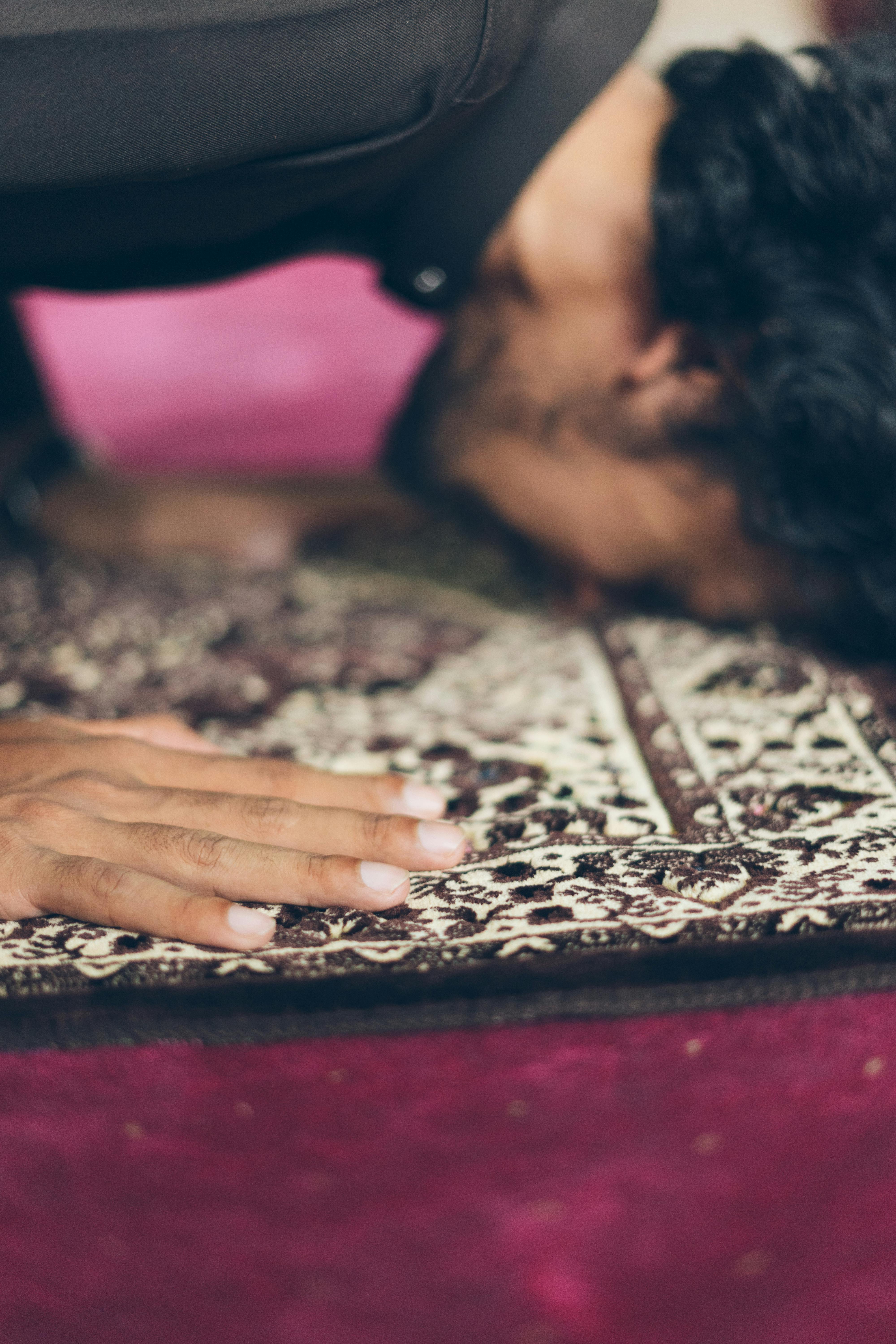 Bezpłatne Osoba oddająca się modlitwie na wzorzystym dywanie w pomieszczeniu. Zdjęcie z galerii