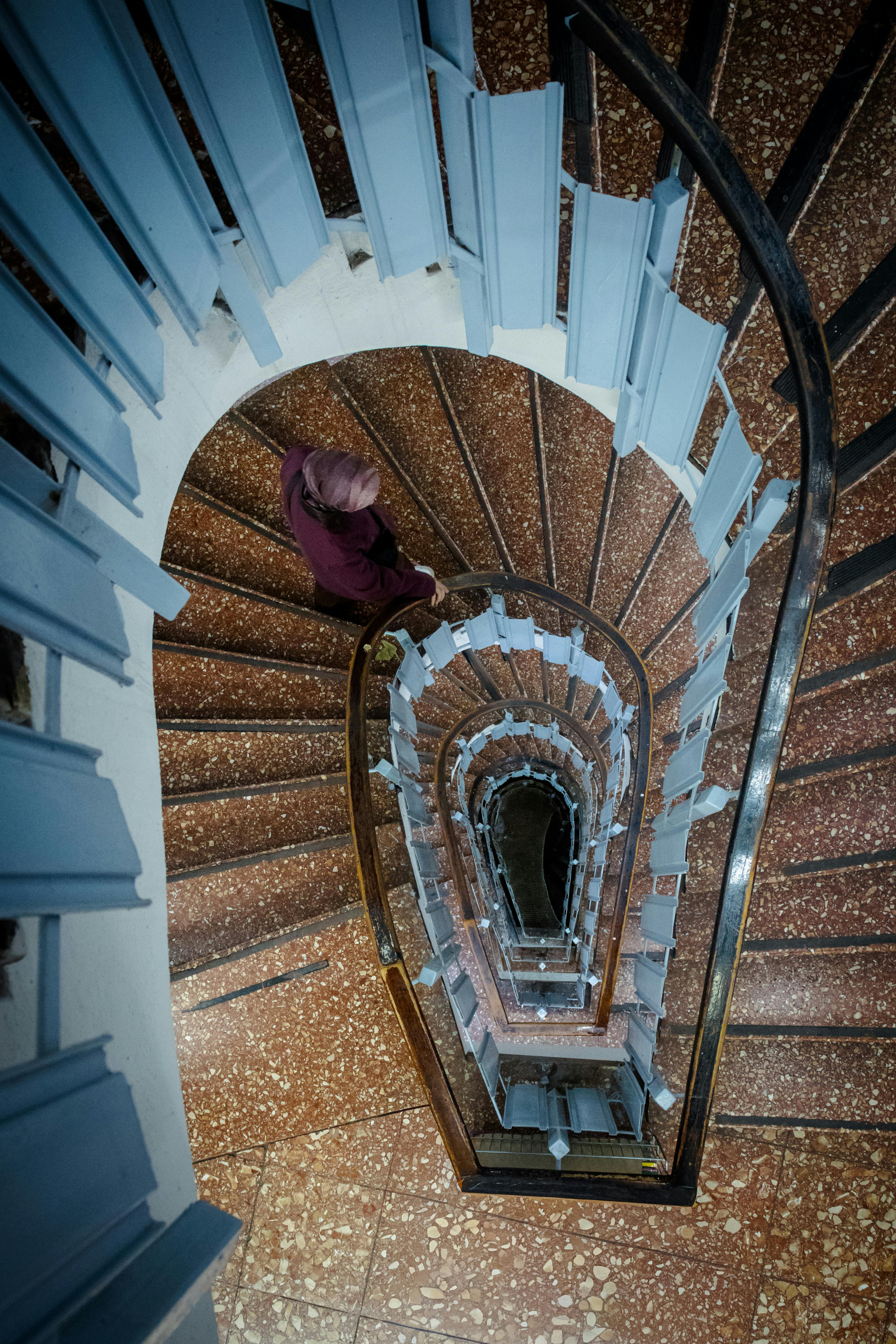 Ilmainen Ylhäältä päin henkilö laskeutuu sisätiloissa kierreportaita pitkin. Kuvapankkikuva