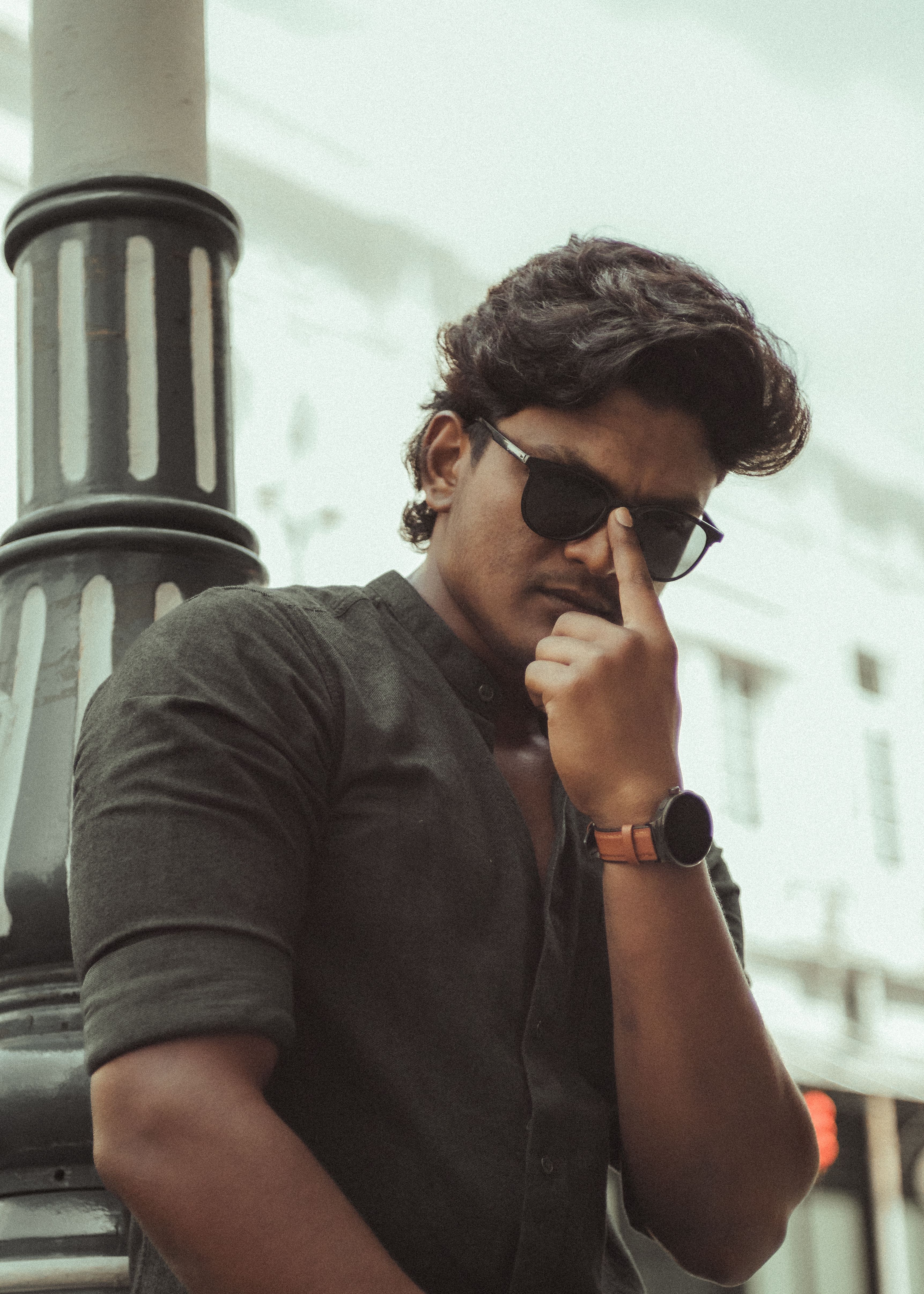 Young man in sunglasses posing against urban backdrop in George Town, Malaysia.