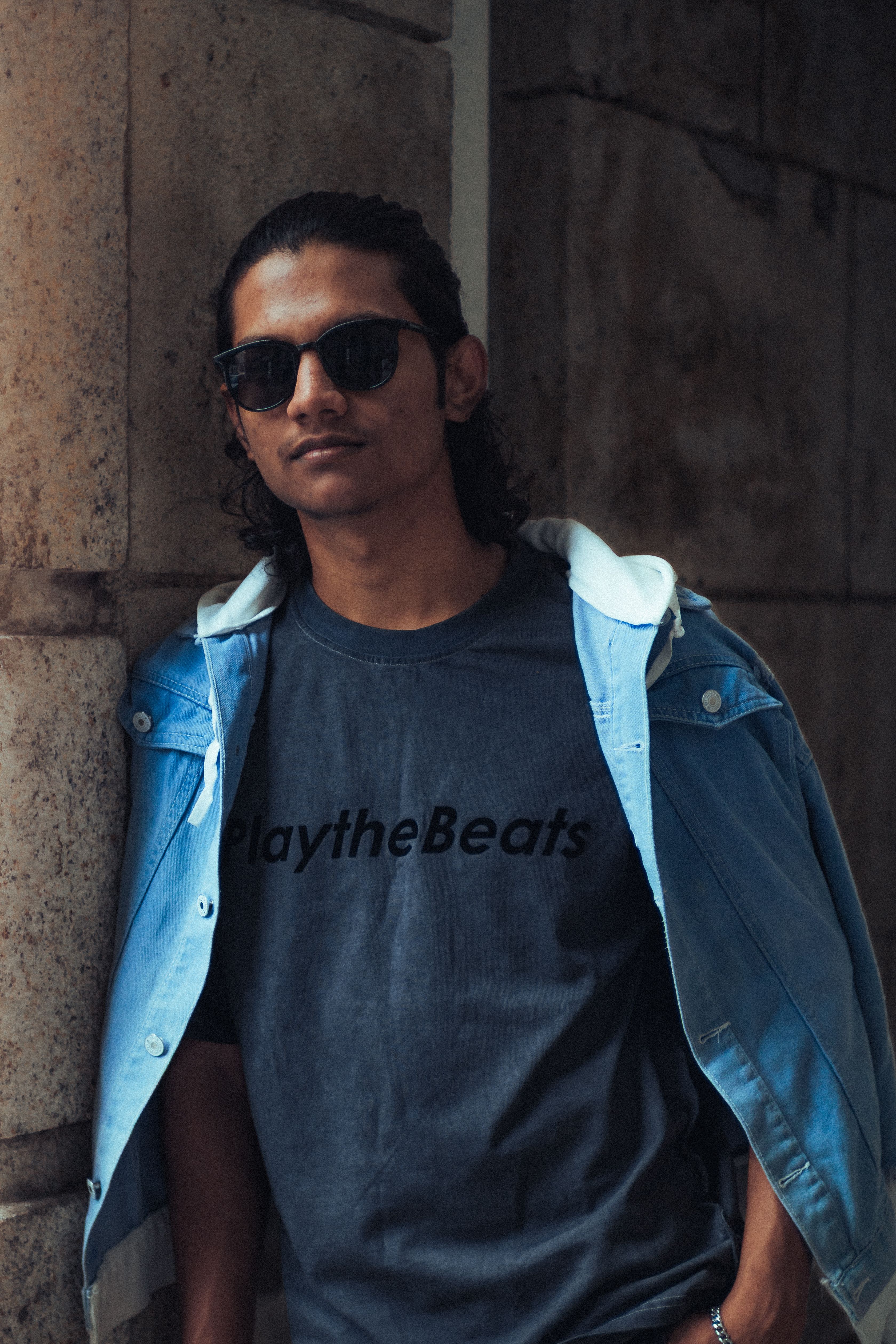 Stylish young adult in sunglasses poses outdoors in George Town, showcasing urban fashion.