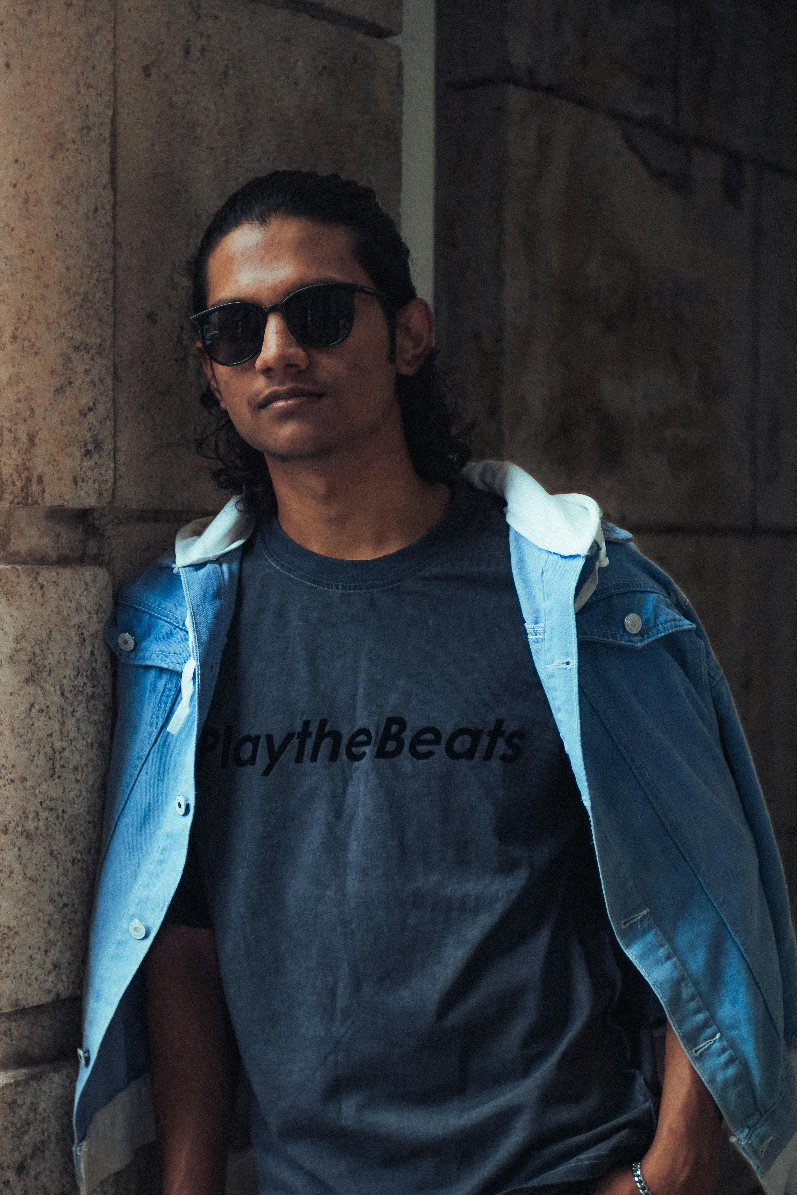 Miễn phí Một người trẻ sành điệu đeo kính râm tạo dáng ngoài trời ở George Town, thể hiện phong cách thời trang thành thị. Ảnh lưu trữ