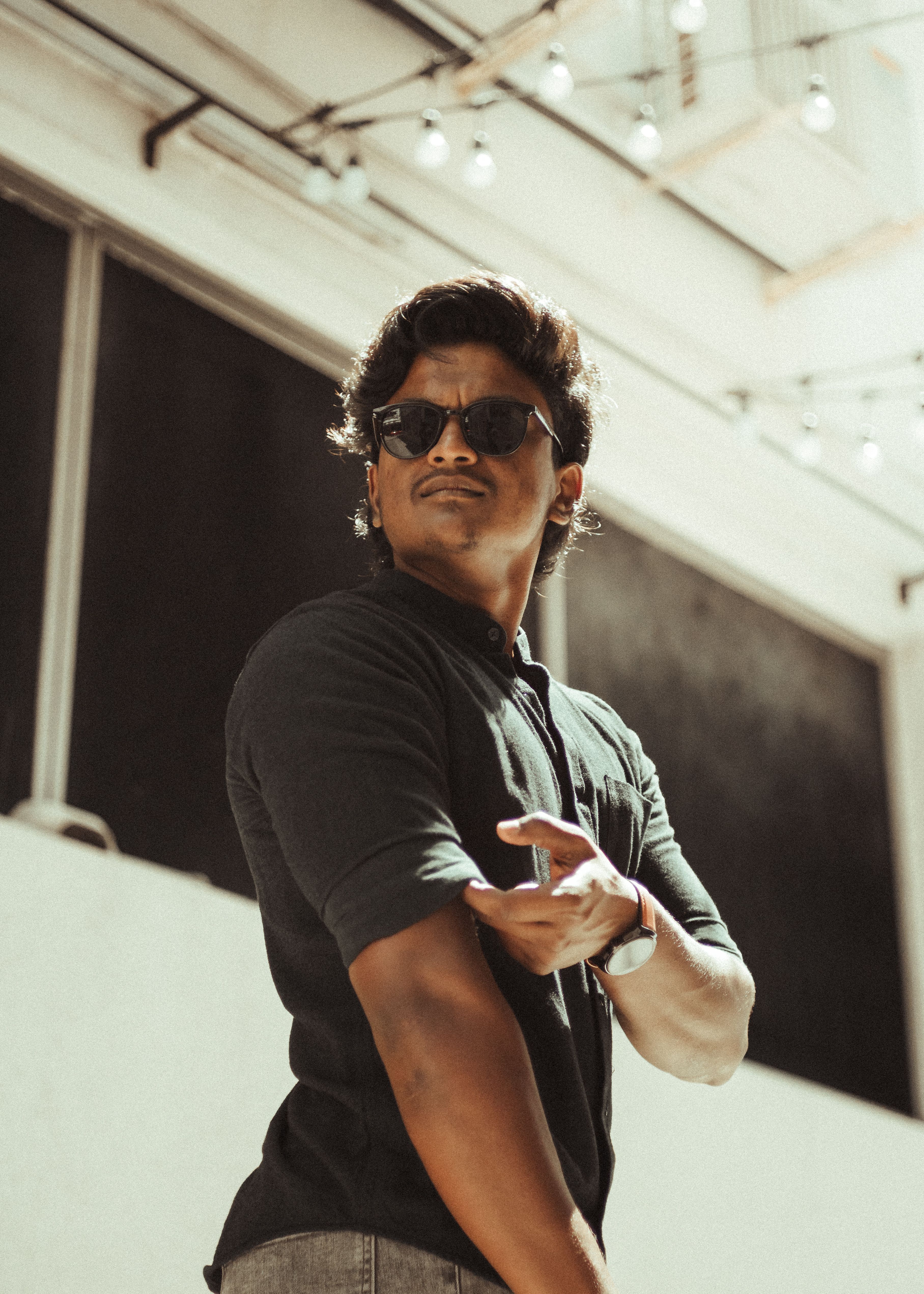 Stylish man in sunglasses posing in an urban setting with modern architecture.