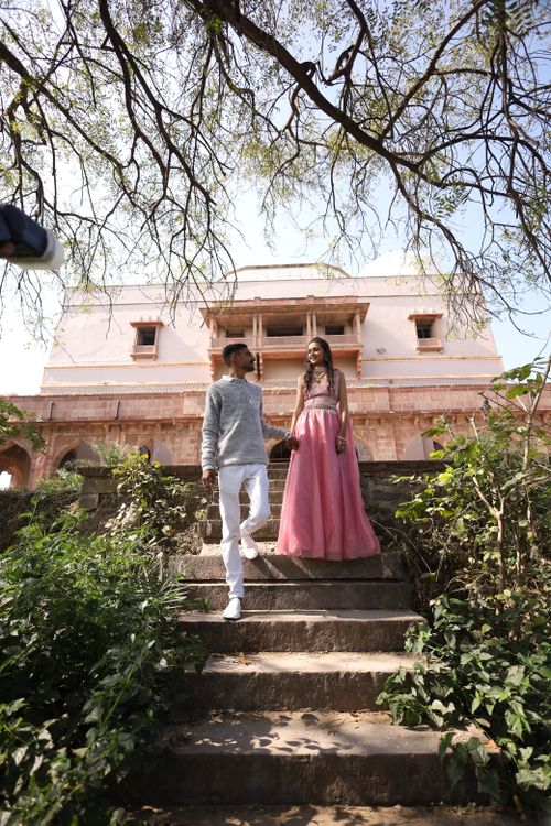 Free A smiling couple poses at a historic fort in India, surrounded by greenery. Stock Photo