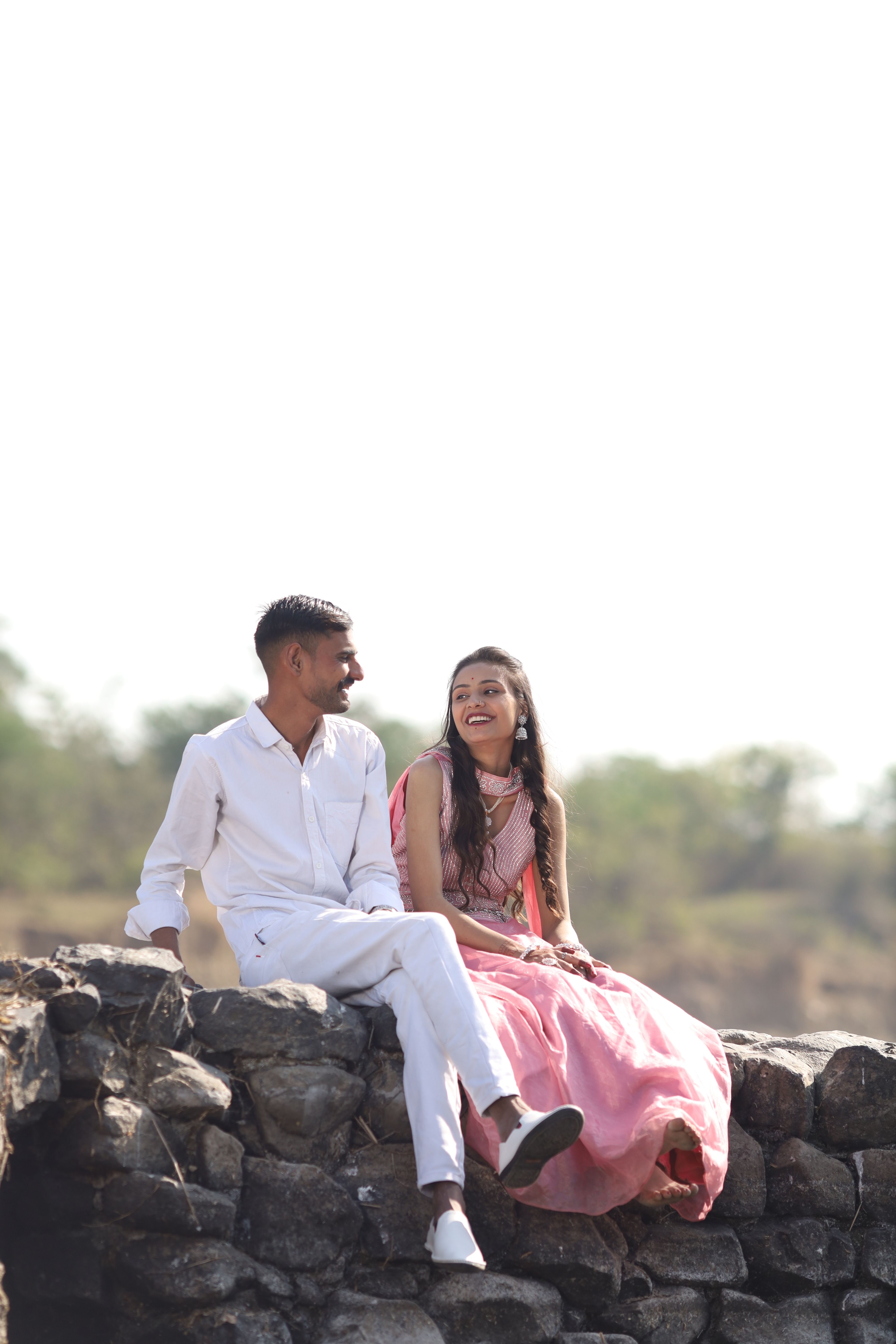 Young Indian Couple Enjoying Outdoors on Stone Wall · Free Stock Photo