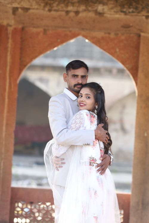 Free An Indian couple beautifully dressed and embracing under a traditional arch. Stock Photo