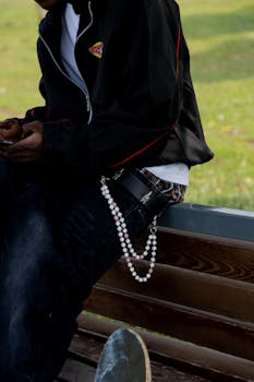 Casual streetwear fashion with accessories on a sunny day, featuring a skateboard and beads.