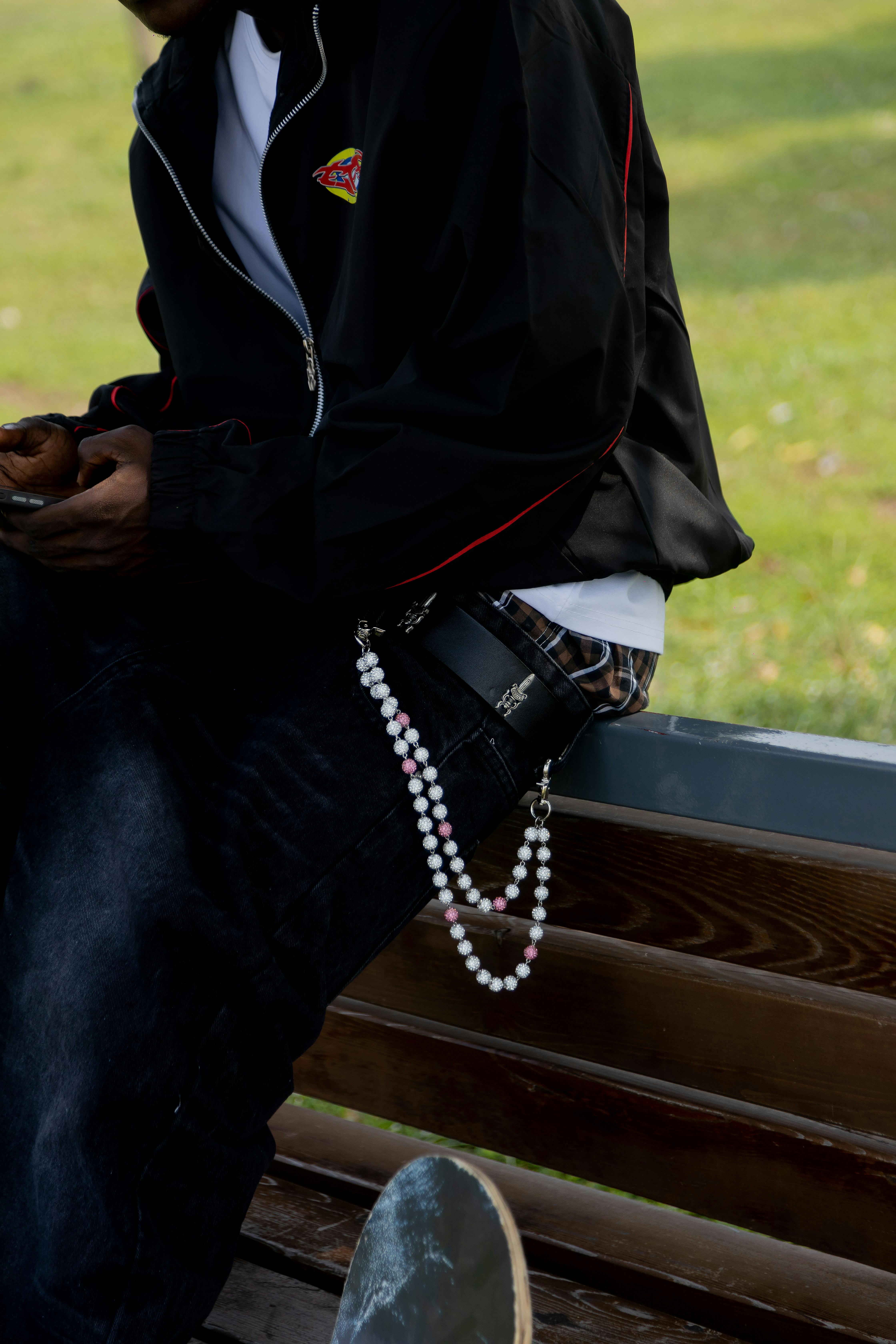 Free Casual streetwear fashion with accessories on a sunny day, featuring a skateboard and beads. Stock Photo