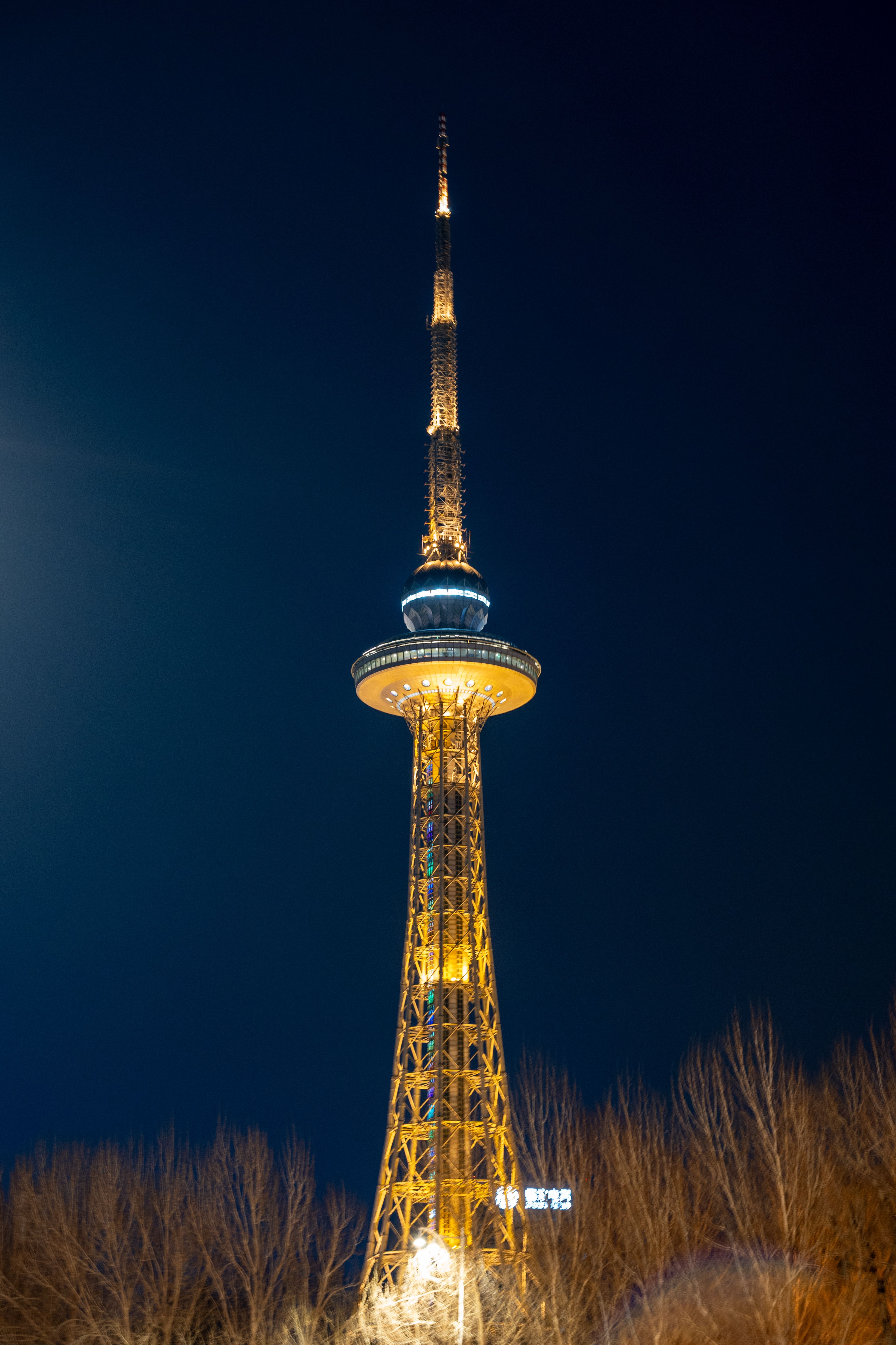Night view of Harbin TV Tower illuminated against a dark sky in winter.