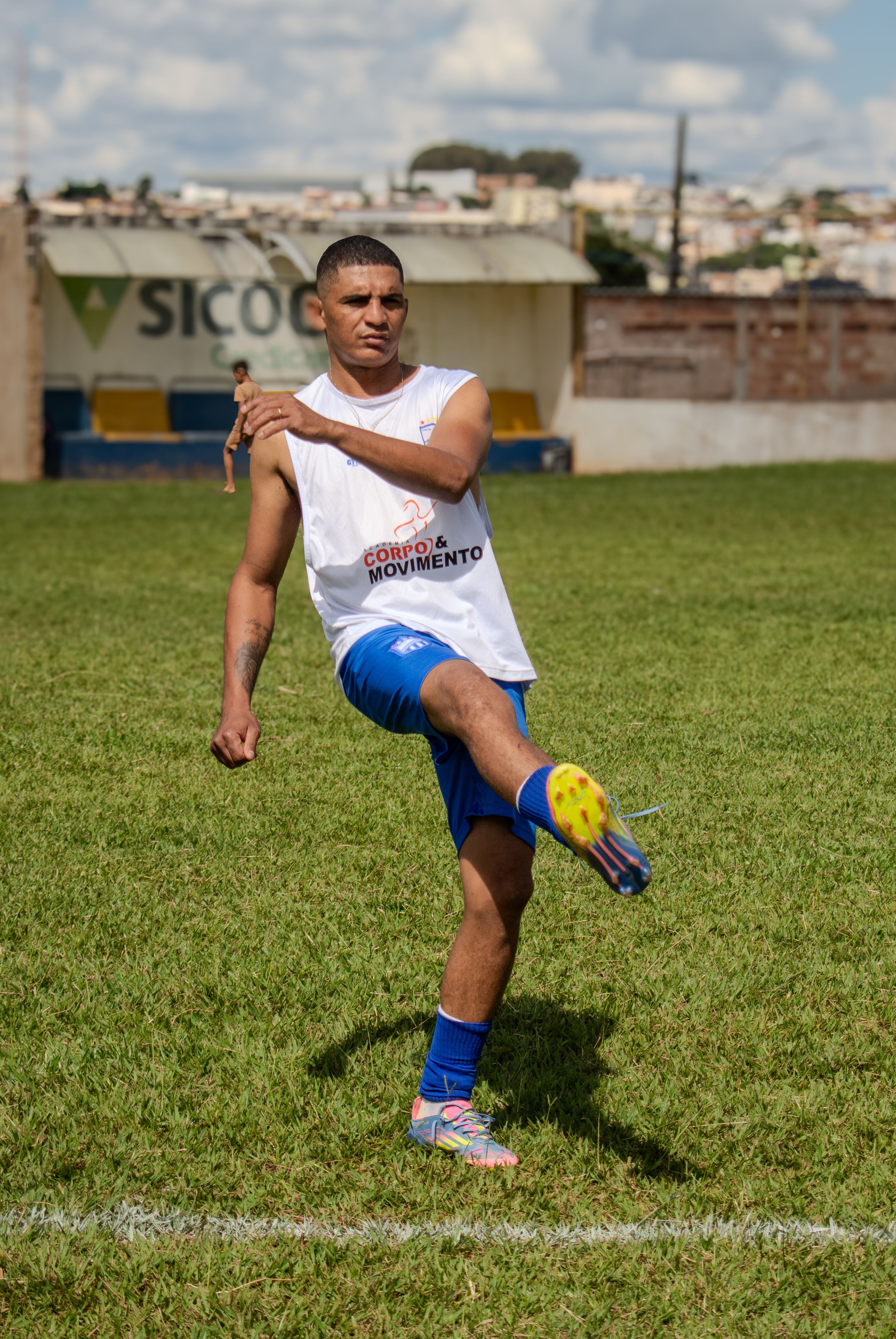 An adult male soccer player in action during practice on a sunny outdoor field.