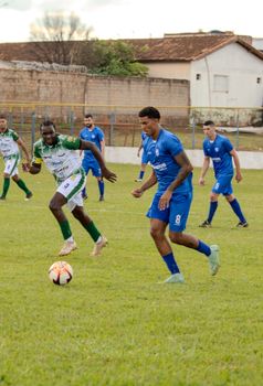 Dynamic scene of amateur soccer players in blue and green uniforms on a grass field.