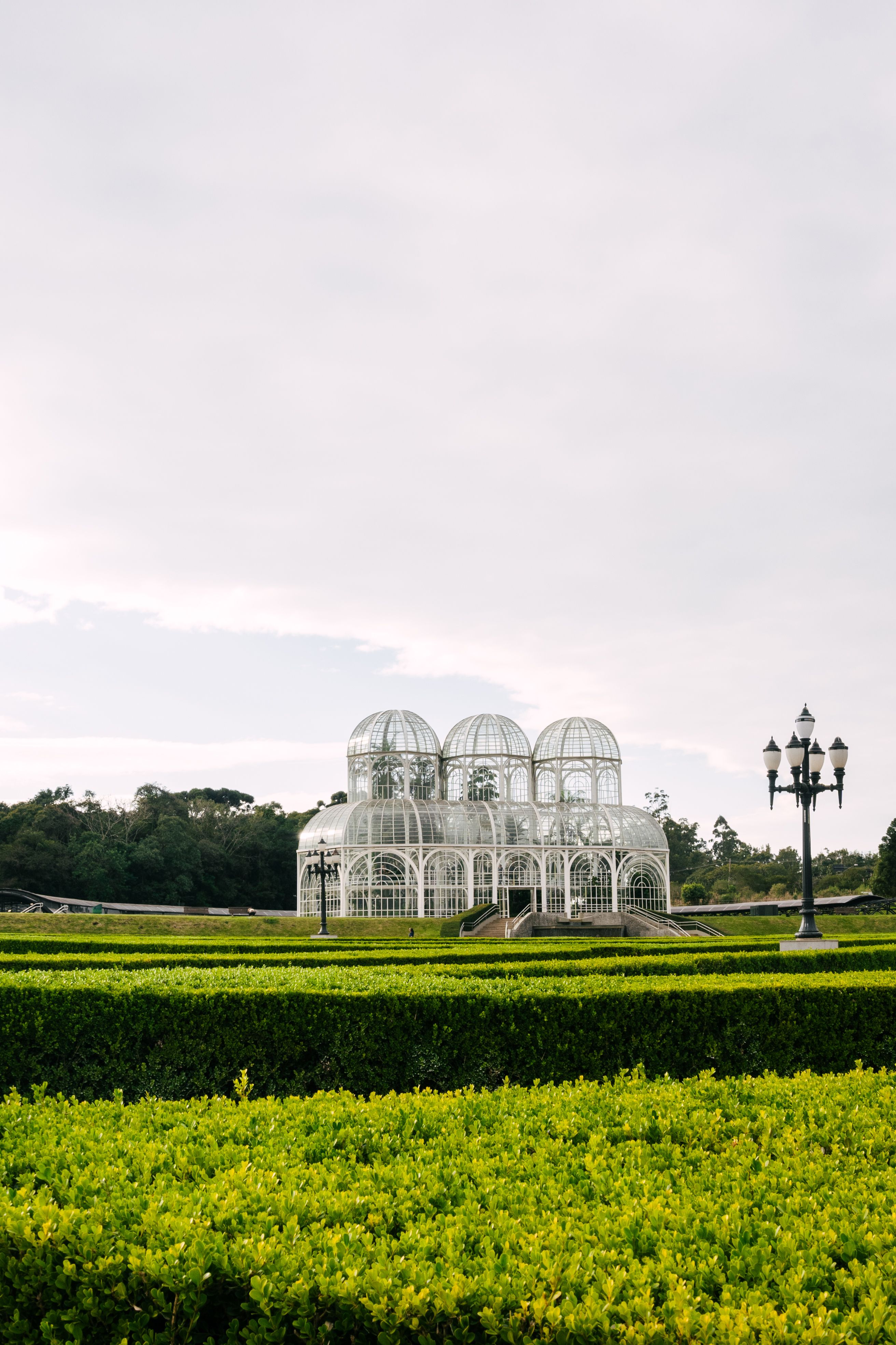 Stunning view of Curitiba's iconic greenhouse in Botanical Garden surrounded by lush green landscape.