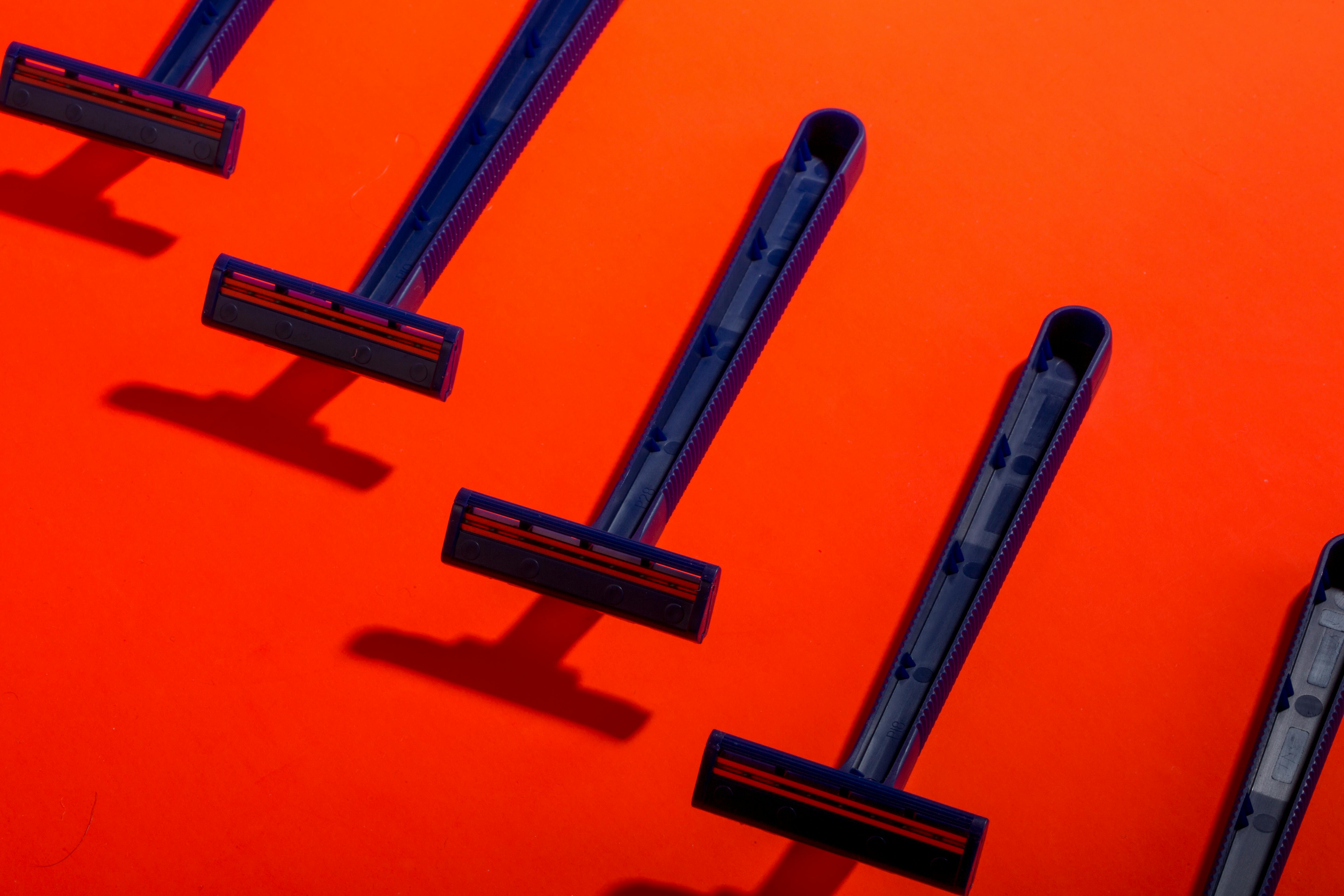 Ücretsiz Canlı turuncu bir arka plan üzerinde düzenli bir şekilde dizilmiş mavi kullanımlık jiletler, çarpıcı bir kontrast oluşturuyor. Stok Fotoğraflar