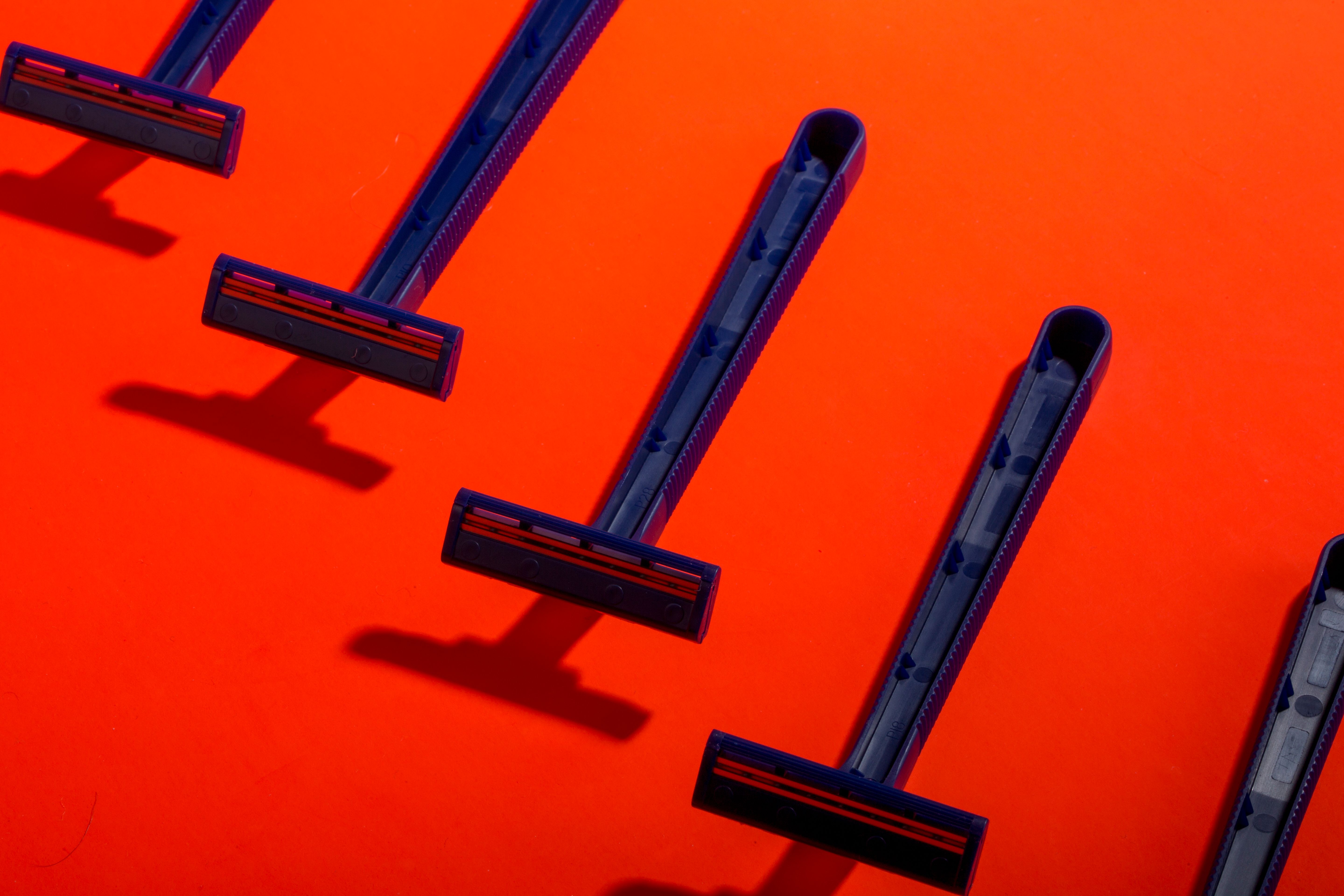 Group of Disposable Razors on Vibrant Orange Background · Free Stock Photo