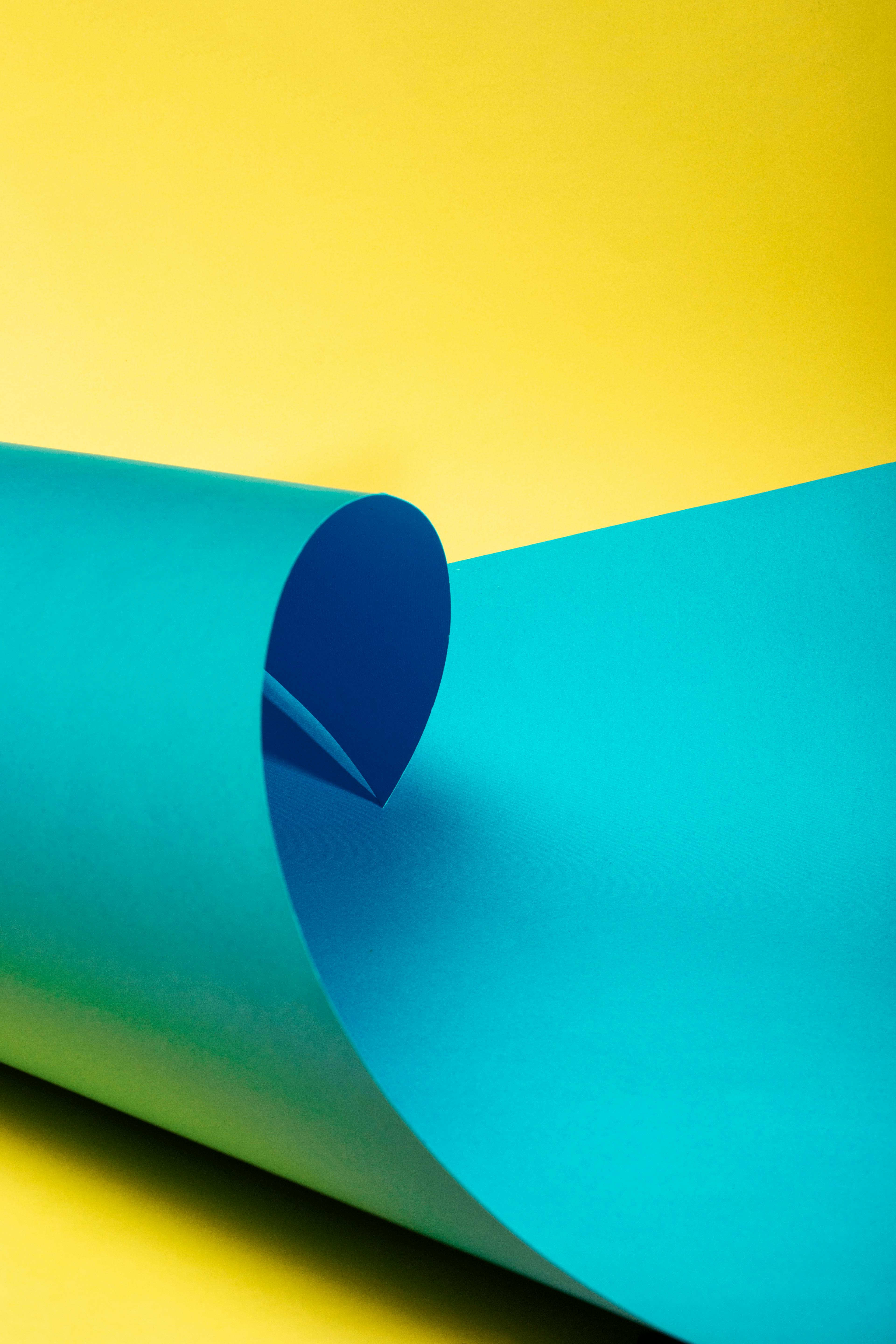 Bezpłatne Kolorowa, abstrakcyjna kompozycja przedstawiająca złożony niebieski papier na żółtym tle, co tworzy żywy kontrast. Zdjęcie z galerii