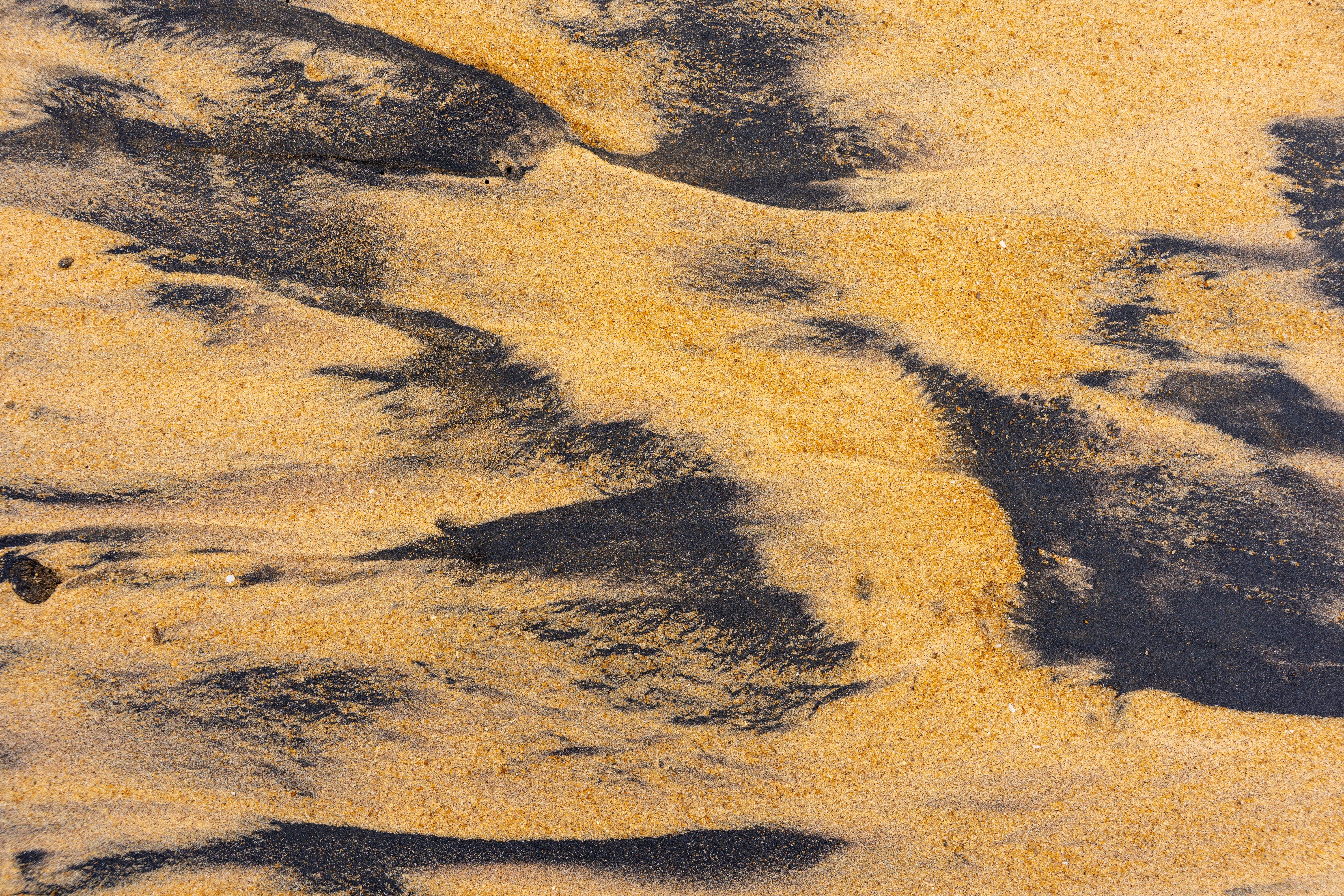 Detailed close-up of sand textures with ilmenite on a beach, highlighting natural patterns.
