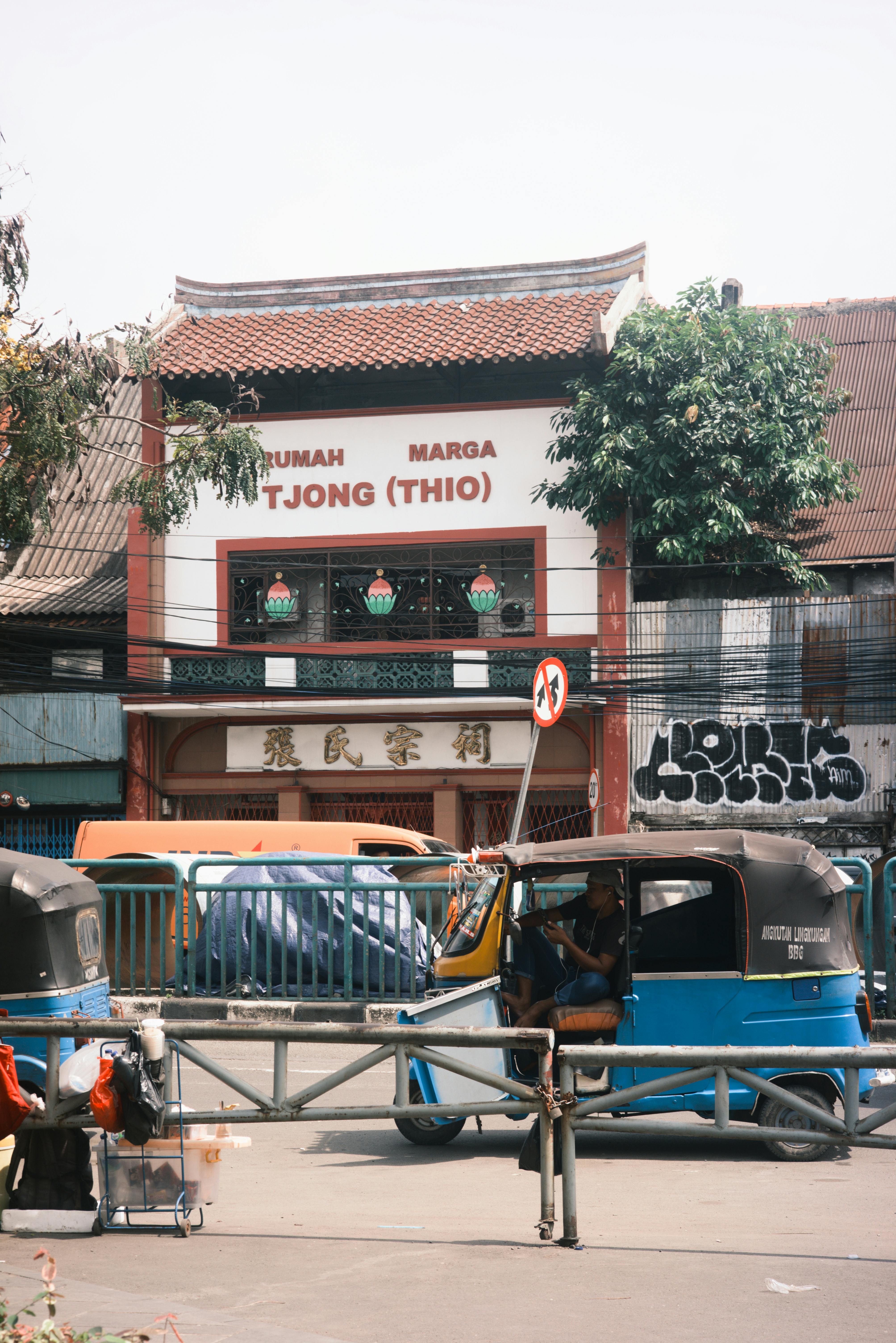 Kostenlos Eine historische Fassade und Bajaj-Fahrzeuge auf einer indonesischen Straße fangen die lokale Kultur und das städtische Leben ein. Stock-Foto