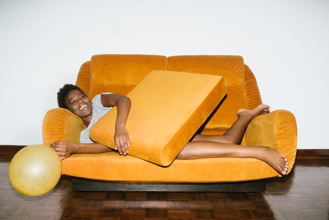 Free Woman Lying on Orange Sofa Stock Photo