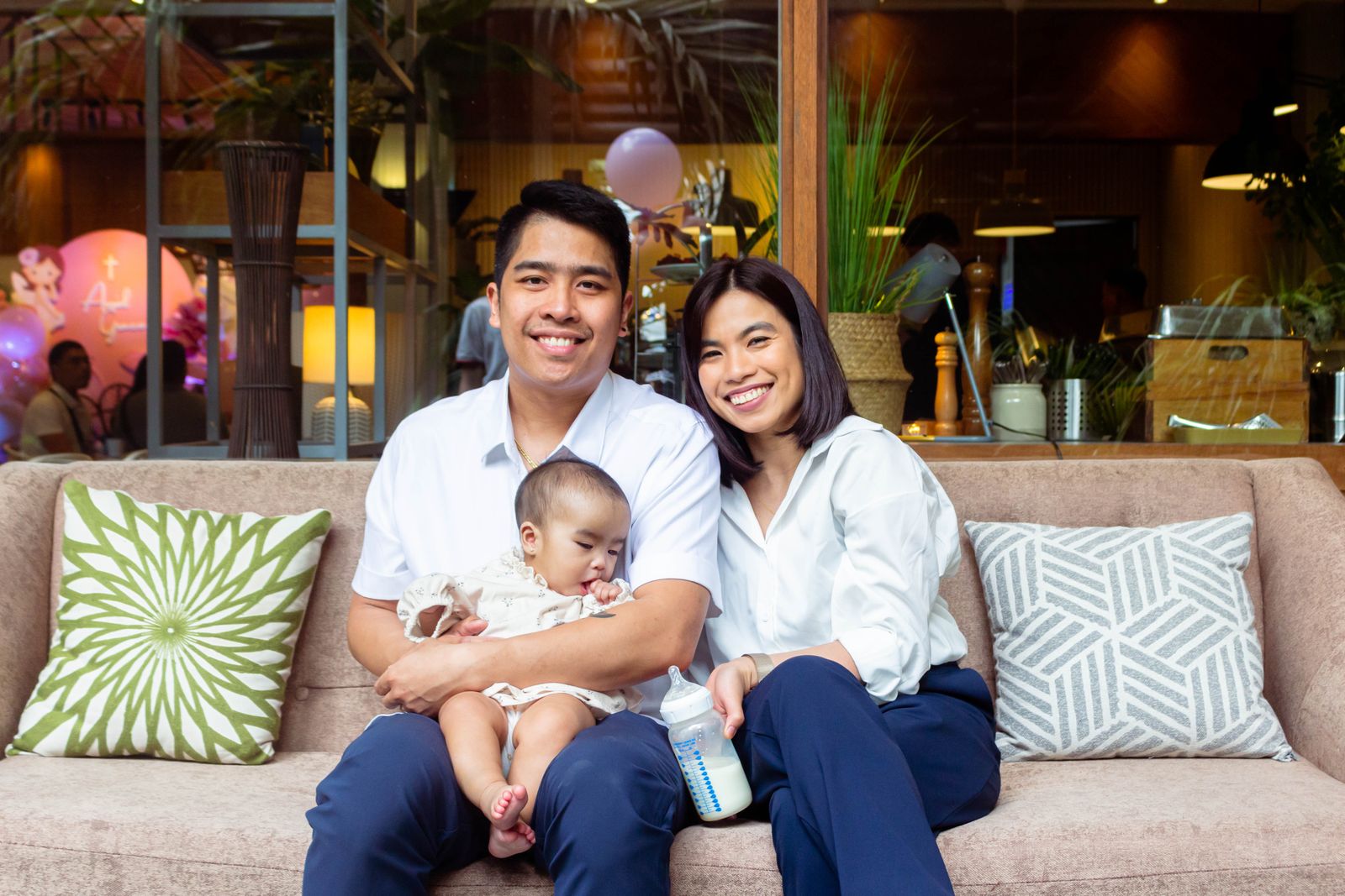 Two adults sitting on a sofa with a baby