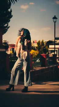 Young woman in stylish outfit posing outdoors in urban area during sunset, exuding confidence and style.