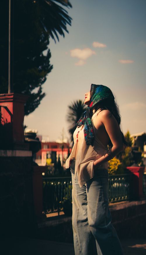 Free A woman with a colorful headscarf enjoys a sunny day outdoors. Captured in a park setting. Stock Photo