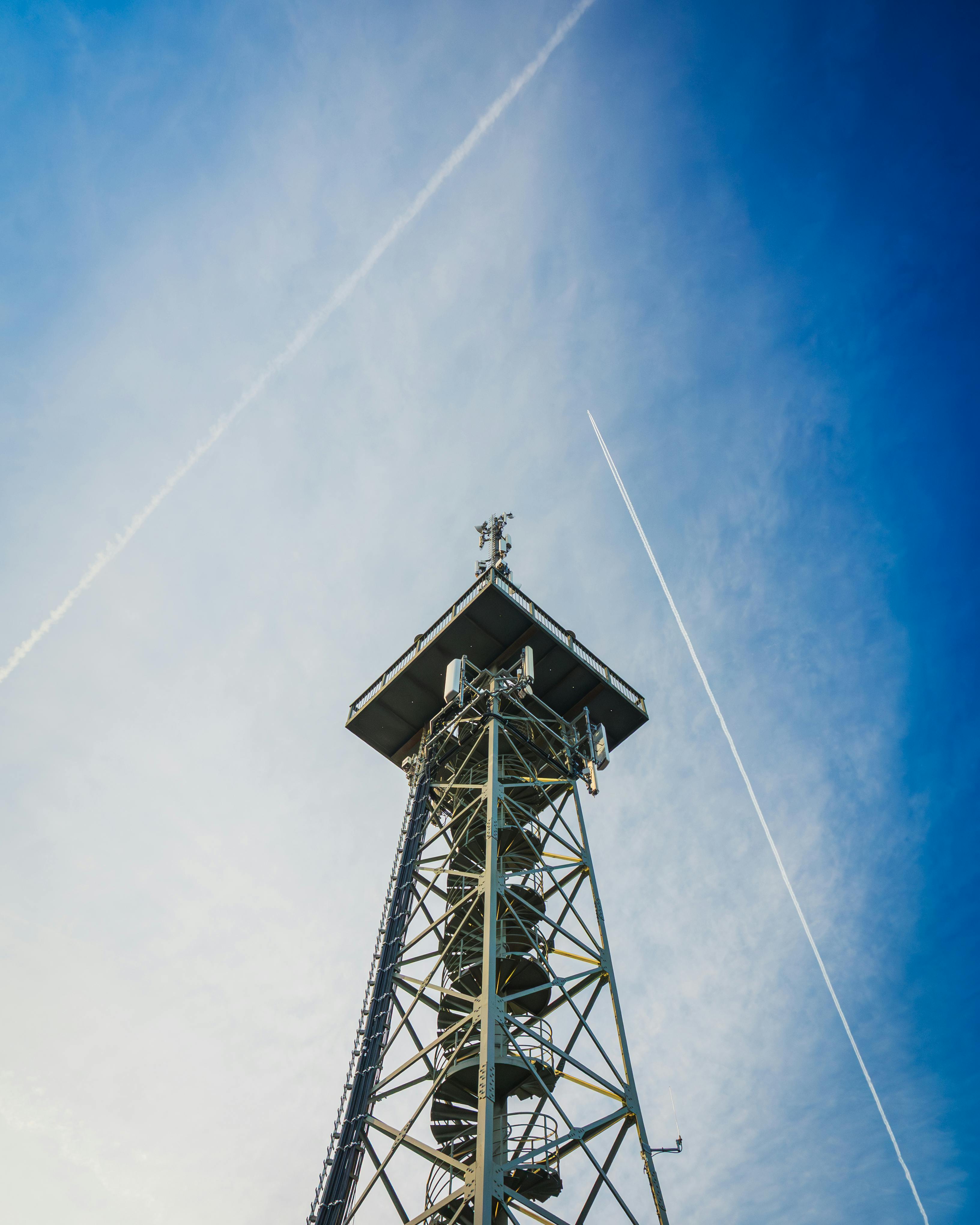 Gratis Metaltårn mod en klar blå himmel med krydsende dampspor fanget i den gyldne time. Lagerfoto