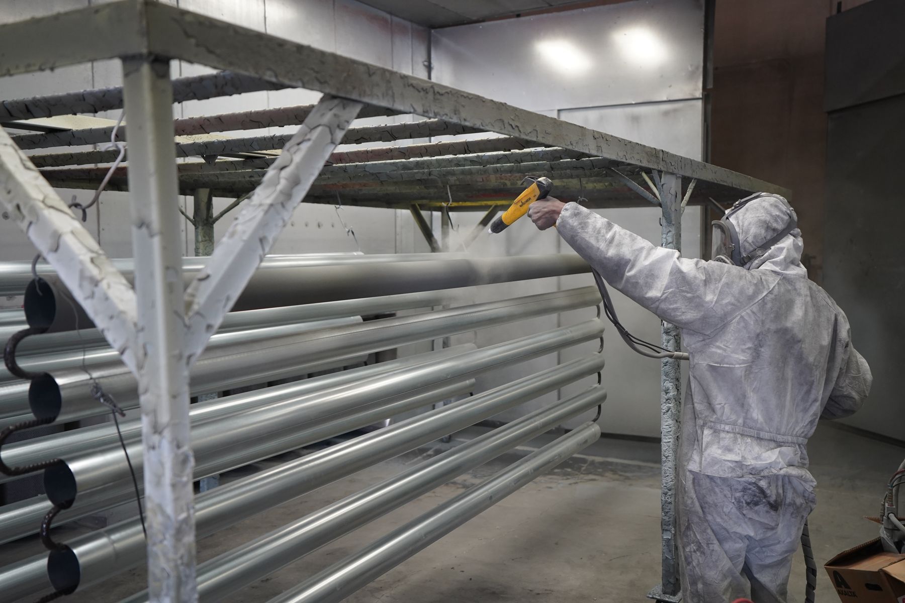 Powder coating in progress — technicians coating long steel profiles in the booth