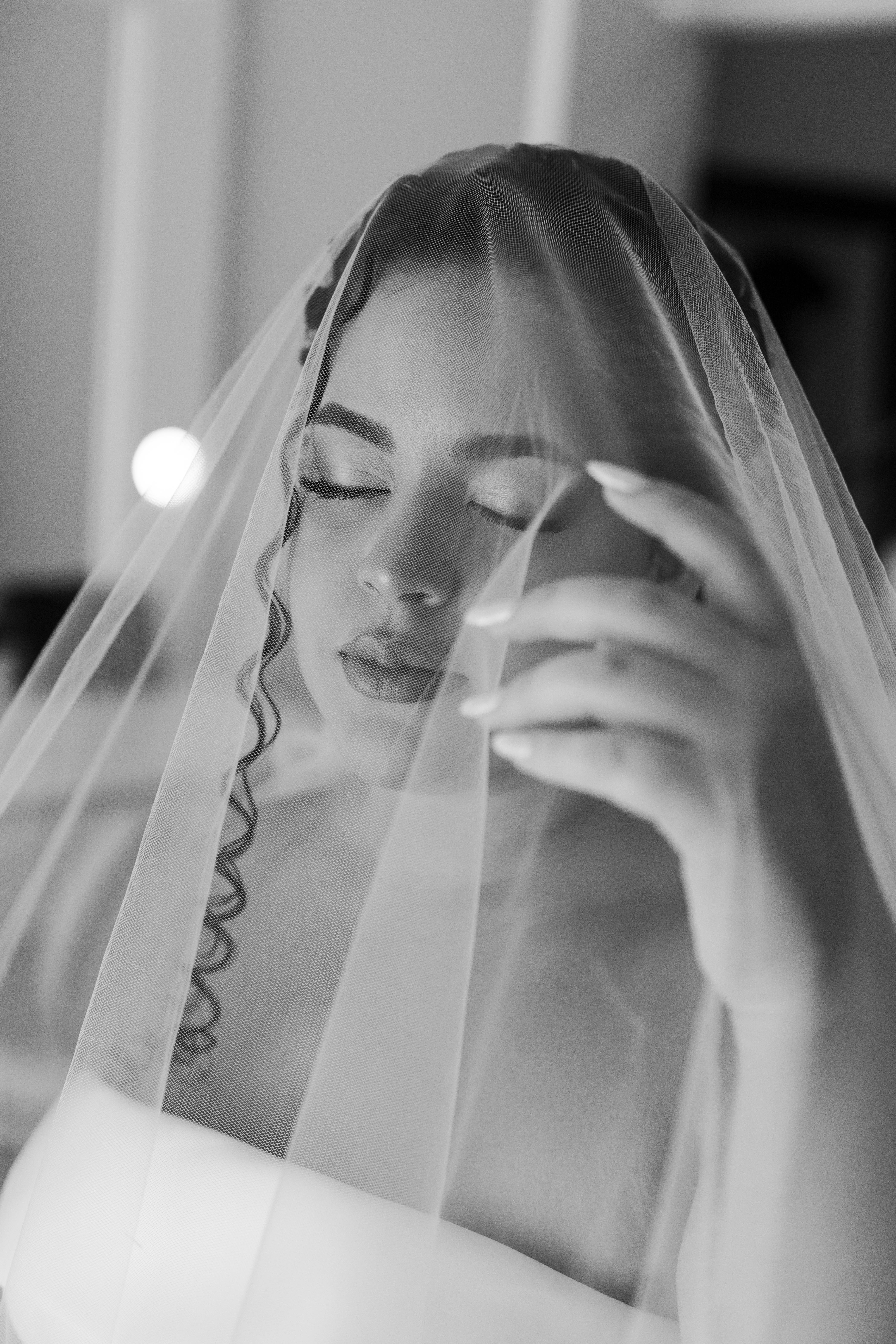 Bezpłatne Elegancki czarno-biały portret ślubny przedstawiający pannę młodą z zamkniętymi oczami, kryjącą się pod powiewającym welonem. Zdjęcie z galerii