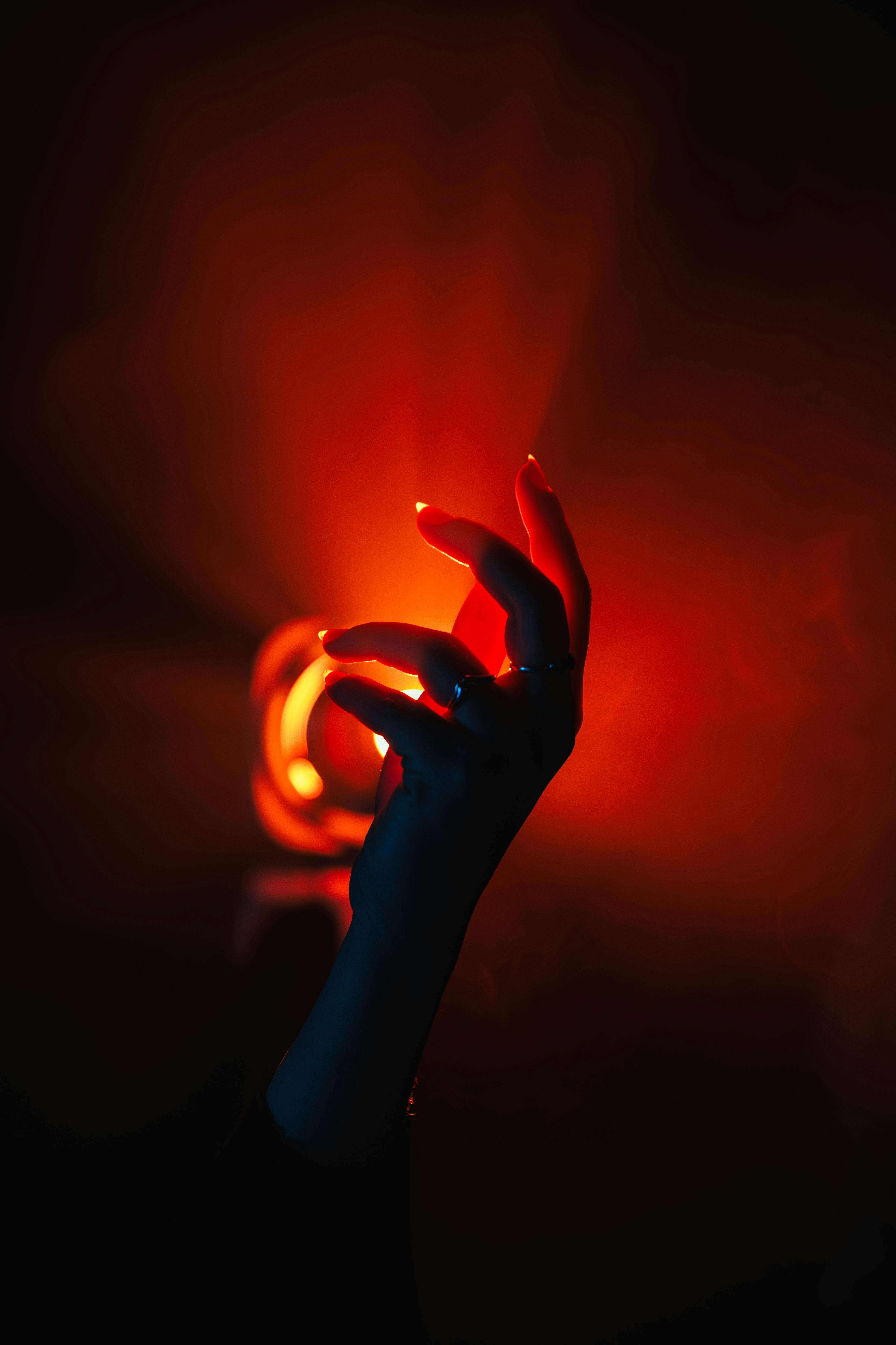 Free A mysterious hand reaches towards a glowing light, creating an ethereal and dramatic atmosphere. Stock Photo
