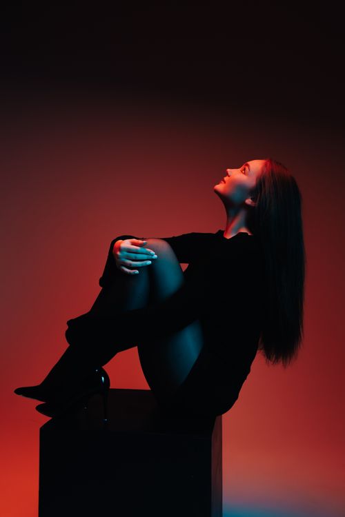 Free Artistic portrait of a woman in silhouette with dramatic red and blue lighting in a studio setting. Stock Photo
