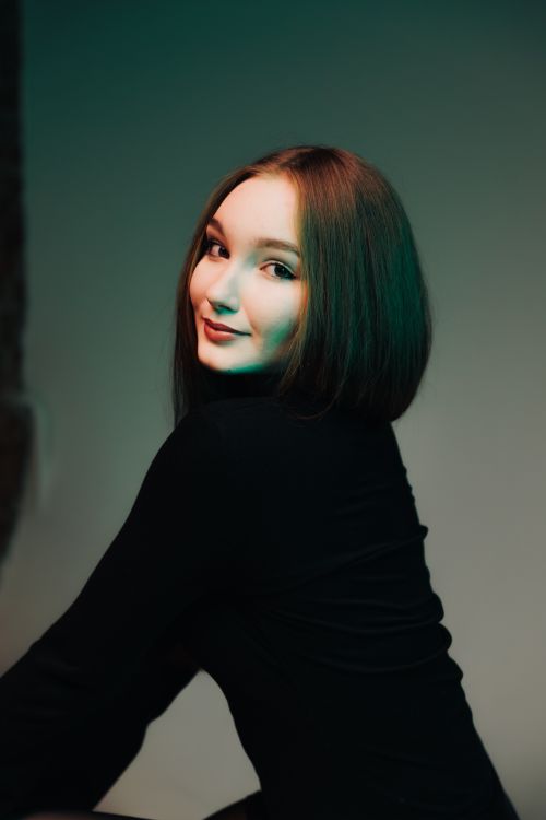 Free A young woman posing confidently with a soft, artistic lighting backdrop. Stock Photo